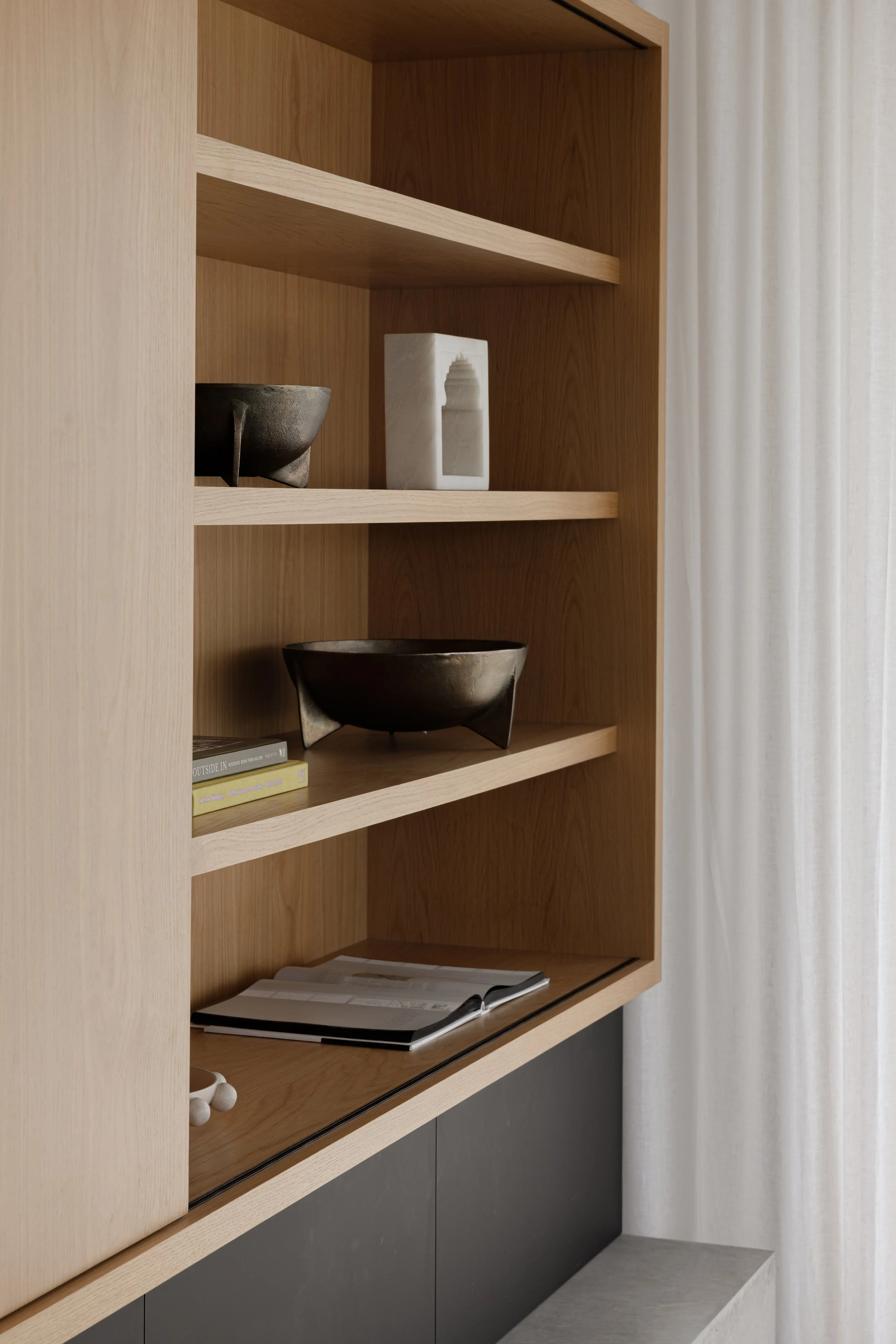 Interior of a modern home with wooden staircase, white walls, a door to the outside, and part of a dining table with chairs visible.