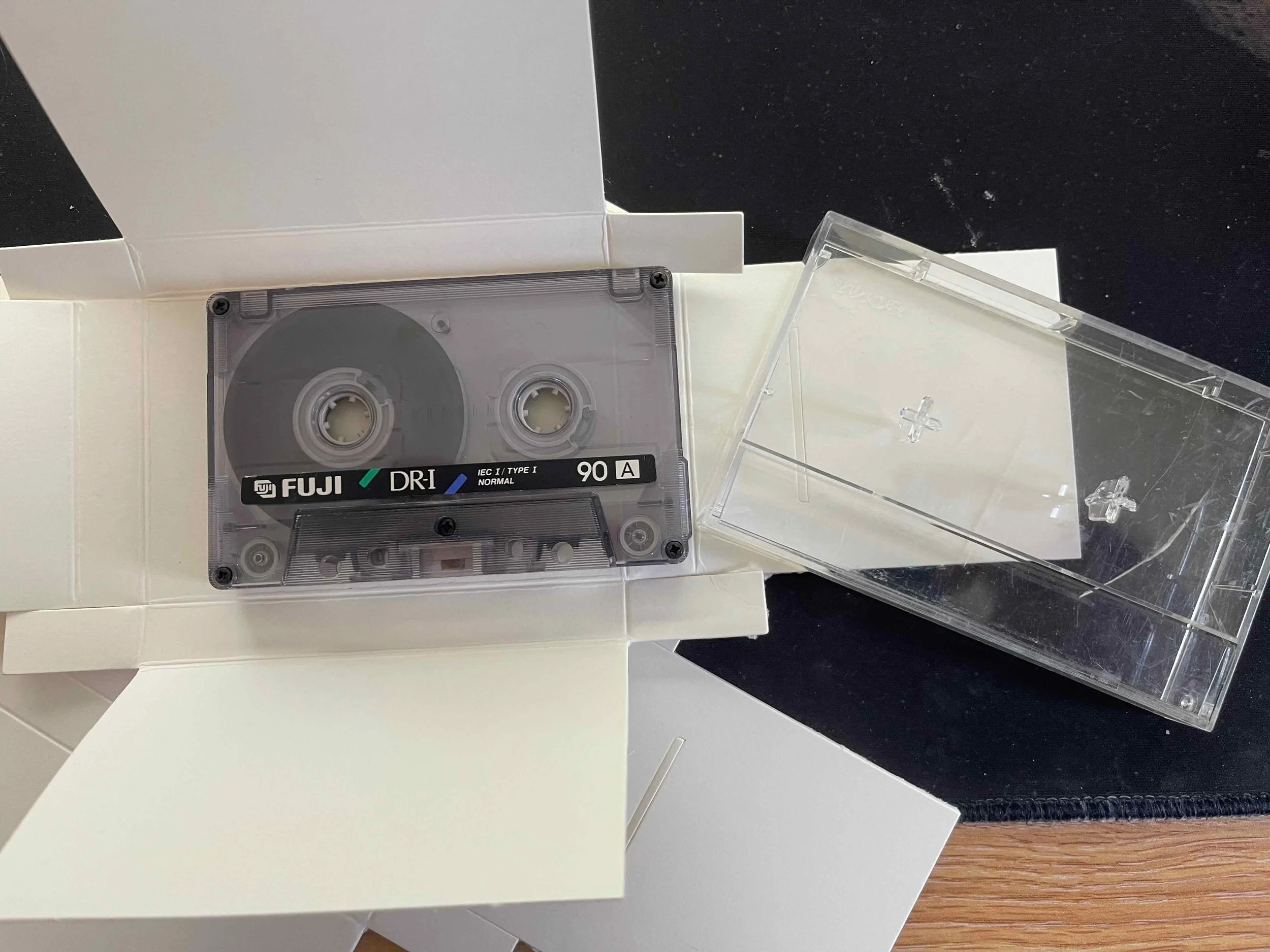 An audio cassette being re-housed from its plastic case into archive-grade, acid-free housing for long term preservation. The audio has been transferred into a digital format for access purposes, and the cassette is now being kept in an archive.