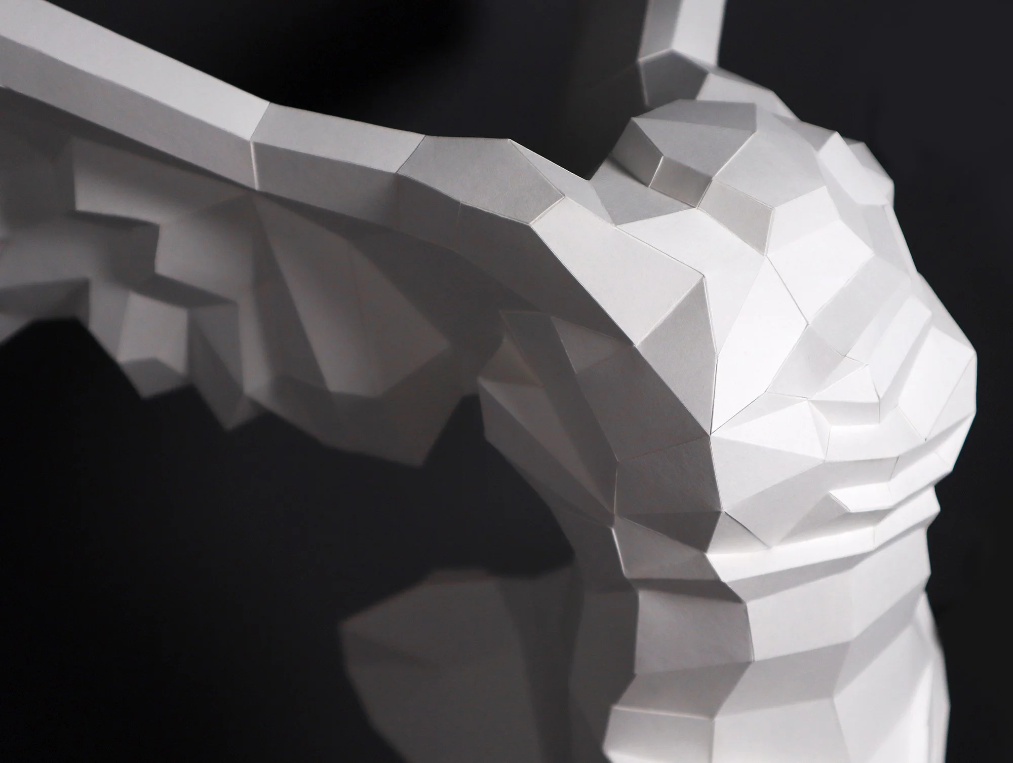 Close-up shot of the geometric wing facets on a LUMISCA Nike sculpture. Showcasing the intricate paper folding and architectural precision of the artwork