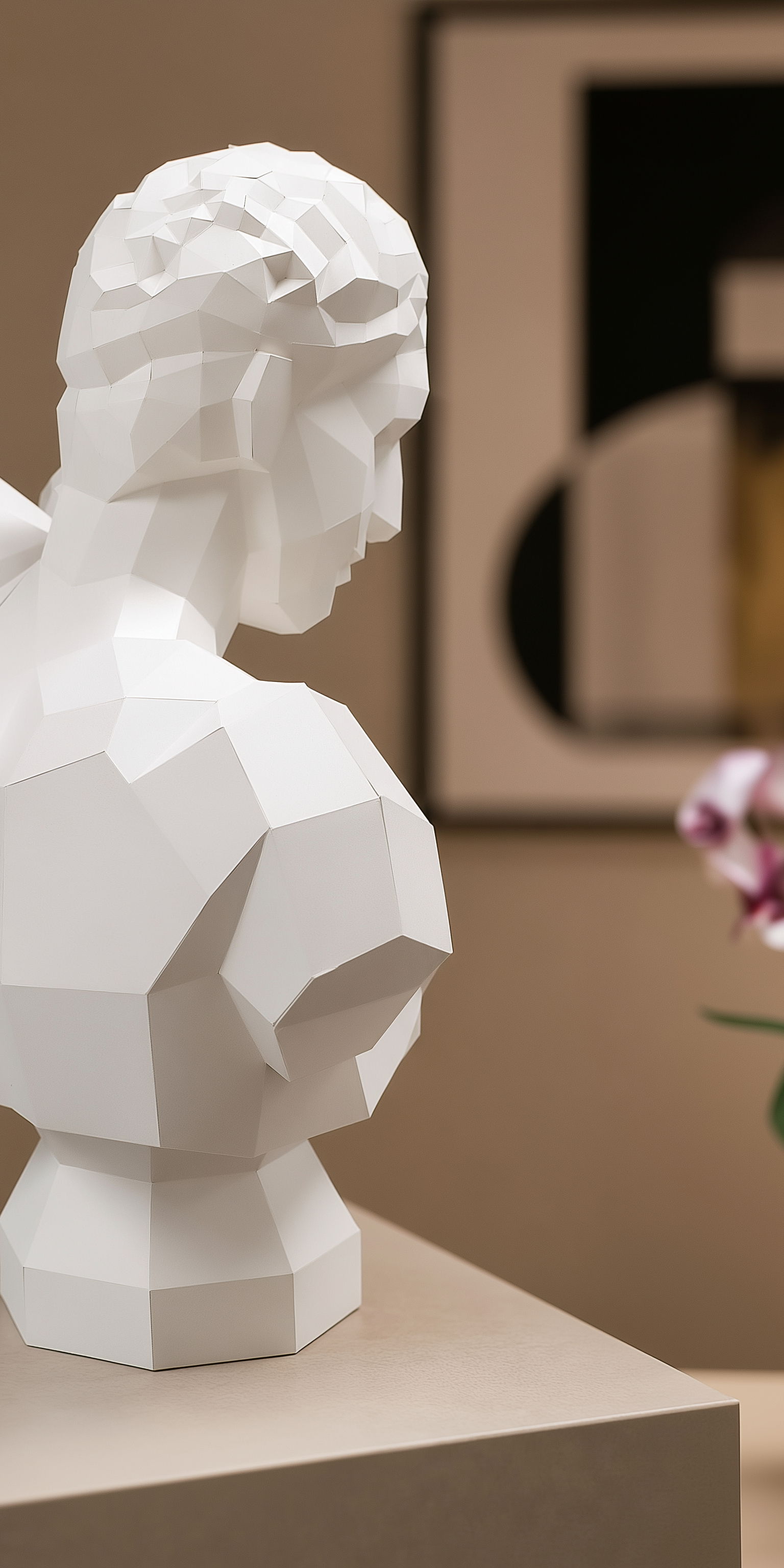 A white geometric paper sculpture bust shaped by folded planes, light, and shadow, displayed in a quiet interior setting