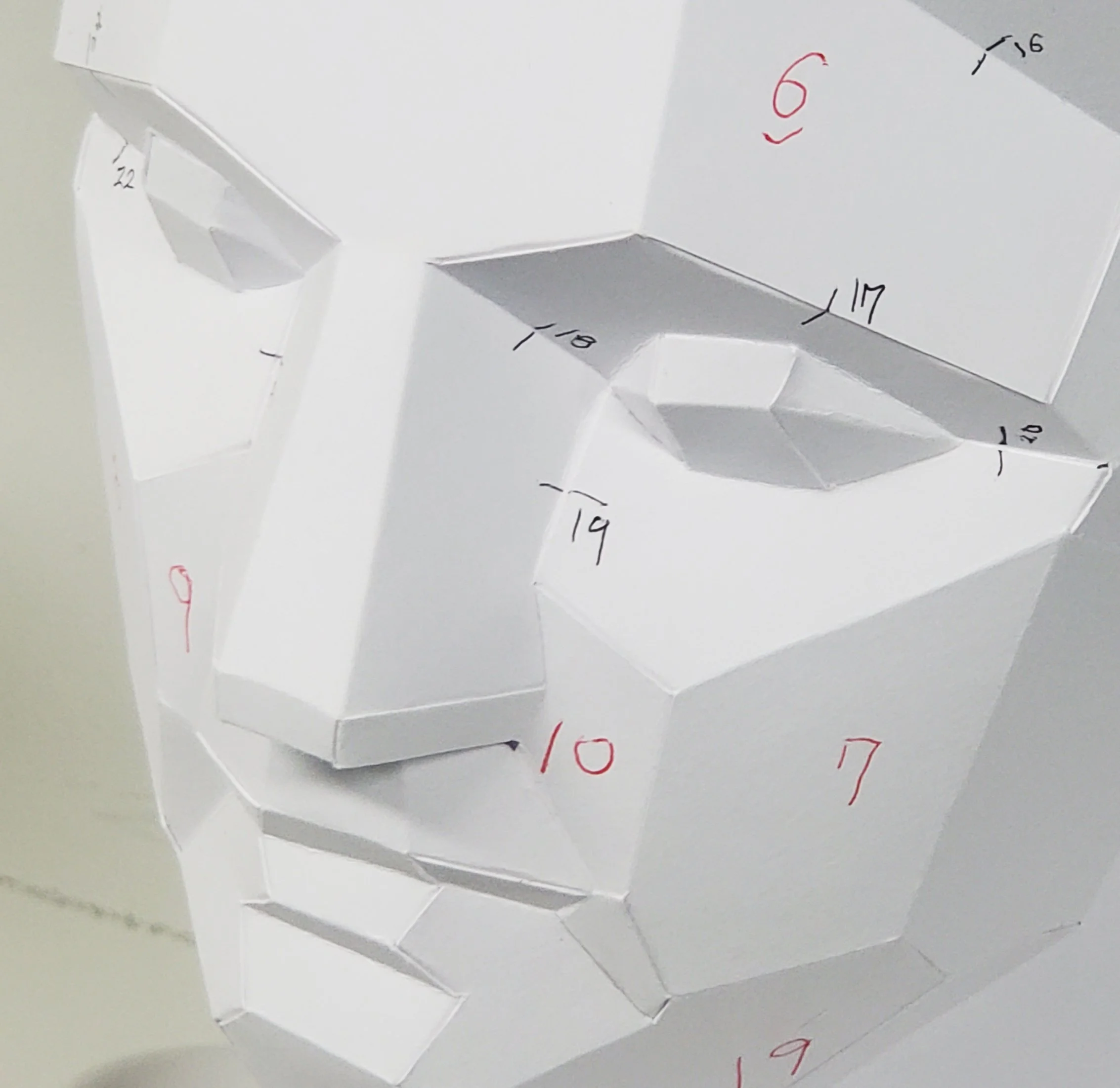 Close-up of a LUMISCA paper sculpture prototype with assembly numbers, demonstrating how invisible supporting planes build the final geometric form.