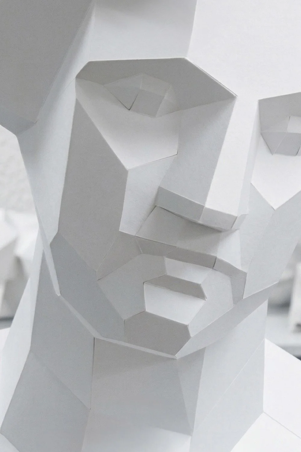 Extreme close-up of the LUMISCA Venus paper sculpture, focusing on the intricate geometric facets of the eye and nose. The high-quality paper texture and sharp low-poly edges demonstrate the 'White Line' mastery under clean, bright lighting.