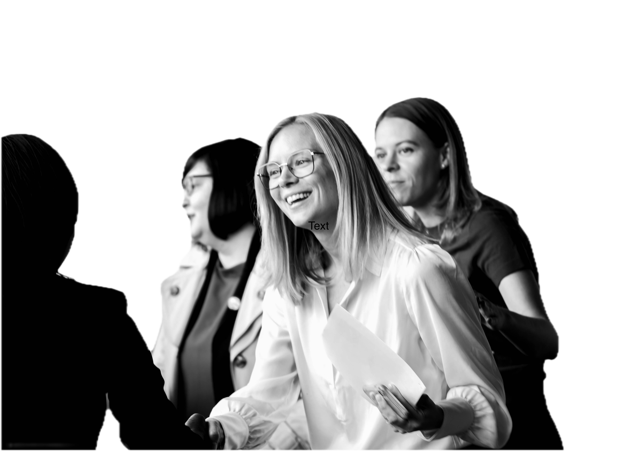 Four women engaged in conversation, smiling and laughing, with one holding a smartphone and colleagues in the background, in black and white.