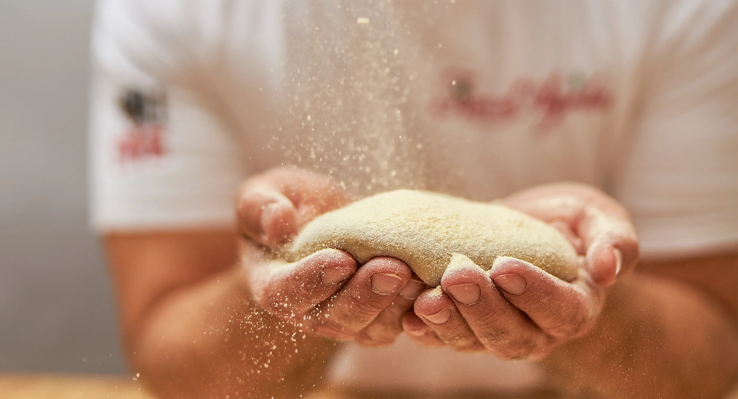 Nahaufnahme: fertig geformte Pizzateigling in zwei Händen