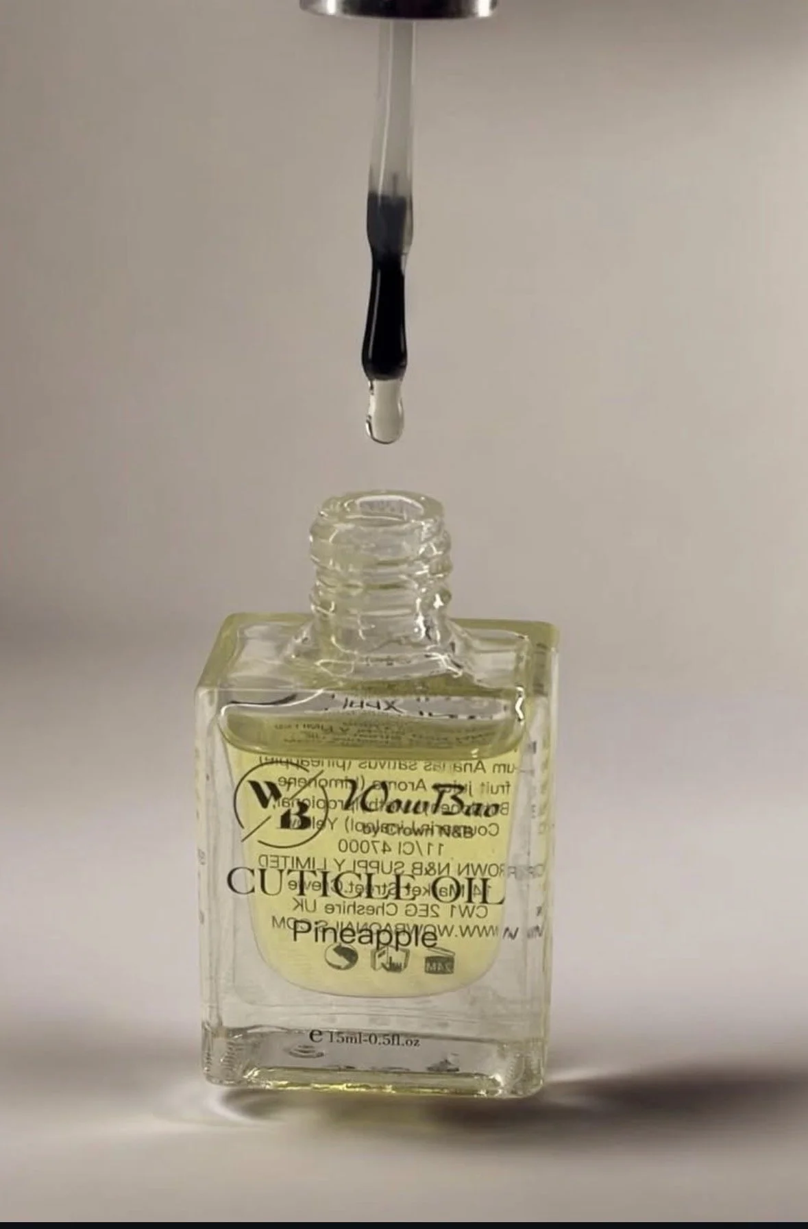 A glass bottle labeled 'The Cutting Board Pineapple' with a dropper above it releasing a drop of liquid into the bottle.