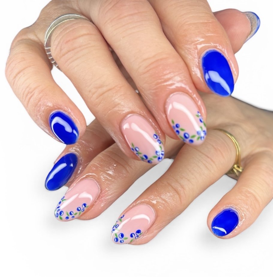 Nail art with alternating bright blue nails and natural nails decorated with small blue and green floral designs.