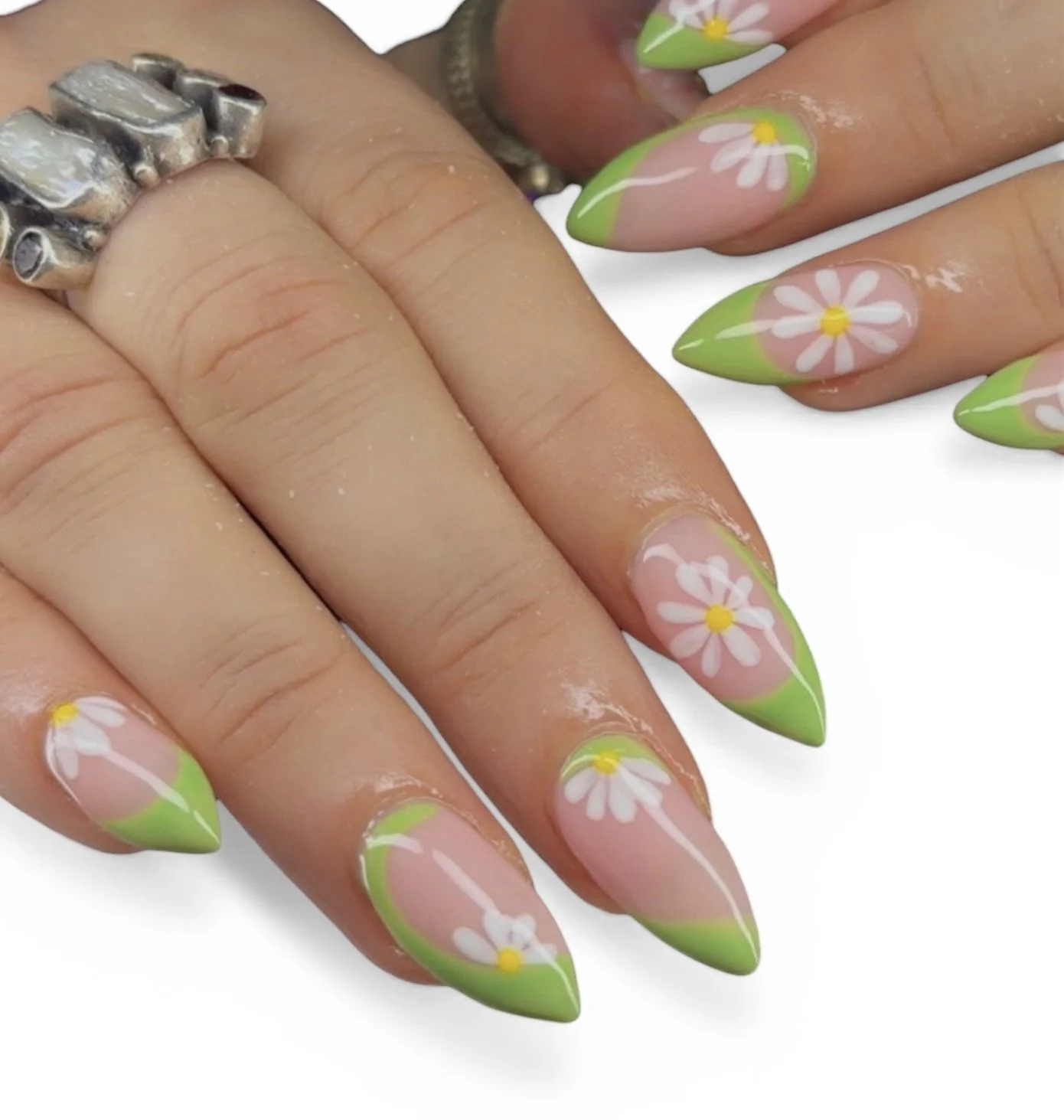 Nails with daisy flower nail art pattern featuring pink and green colors.