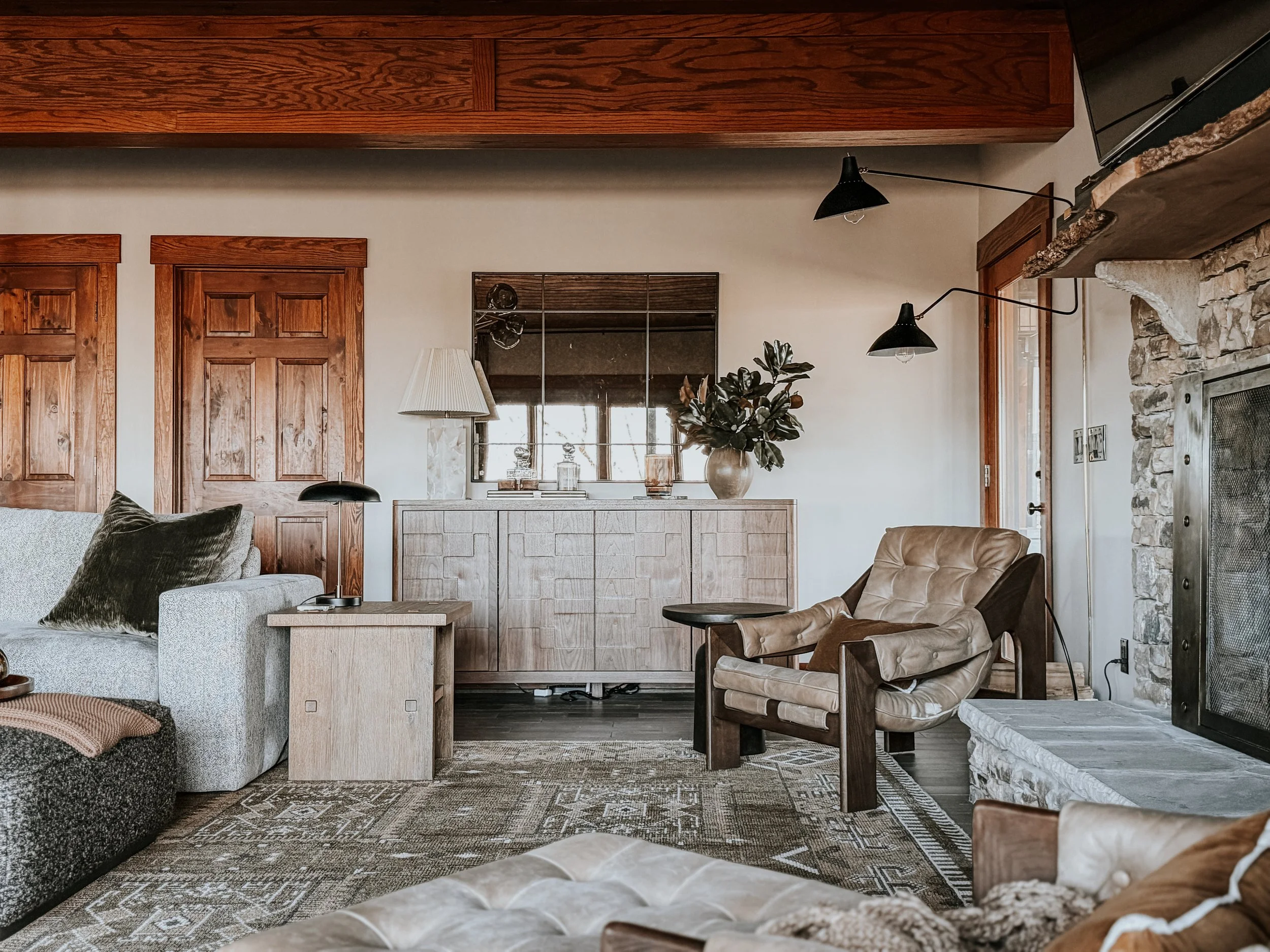 Custom walnut bar and cozy reading nook with leather sling chairs and articulating sconce in a luxury living room designed by Studio Meadow