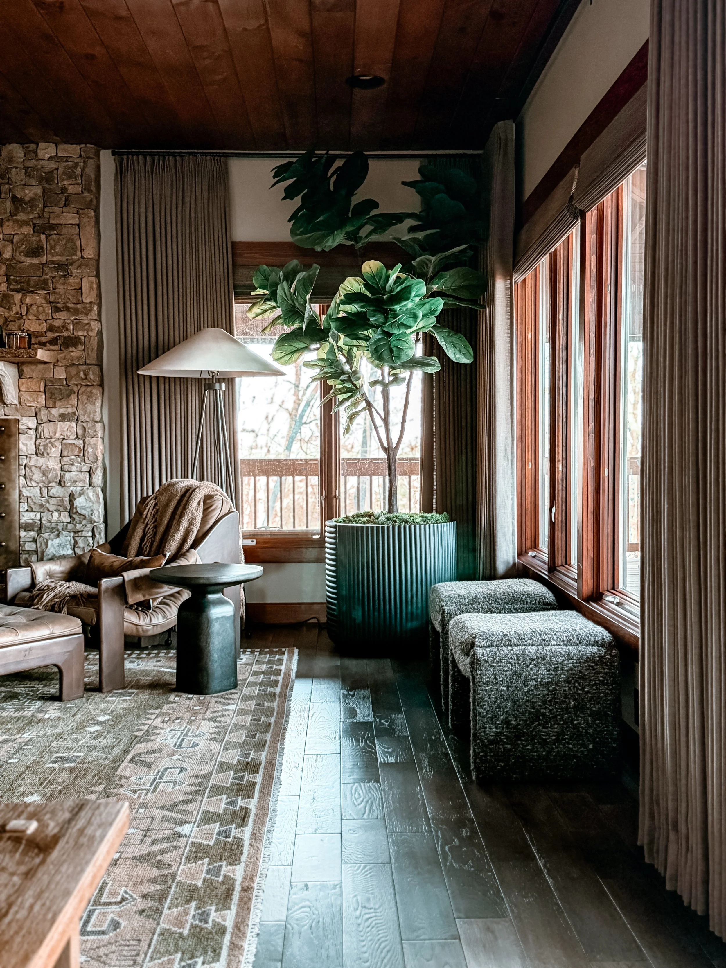 Mountain lodge style living room with stone fireplace, leather seating, and layered materials designed by Studio Meadow in North Georgia