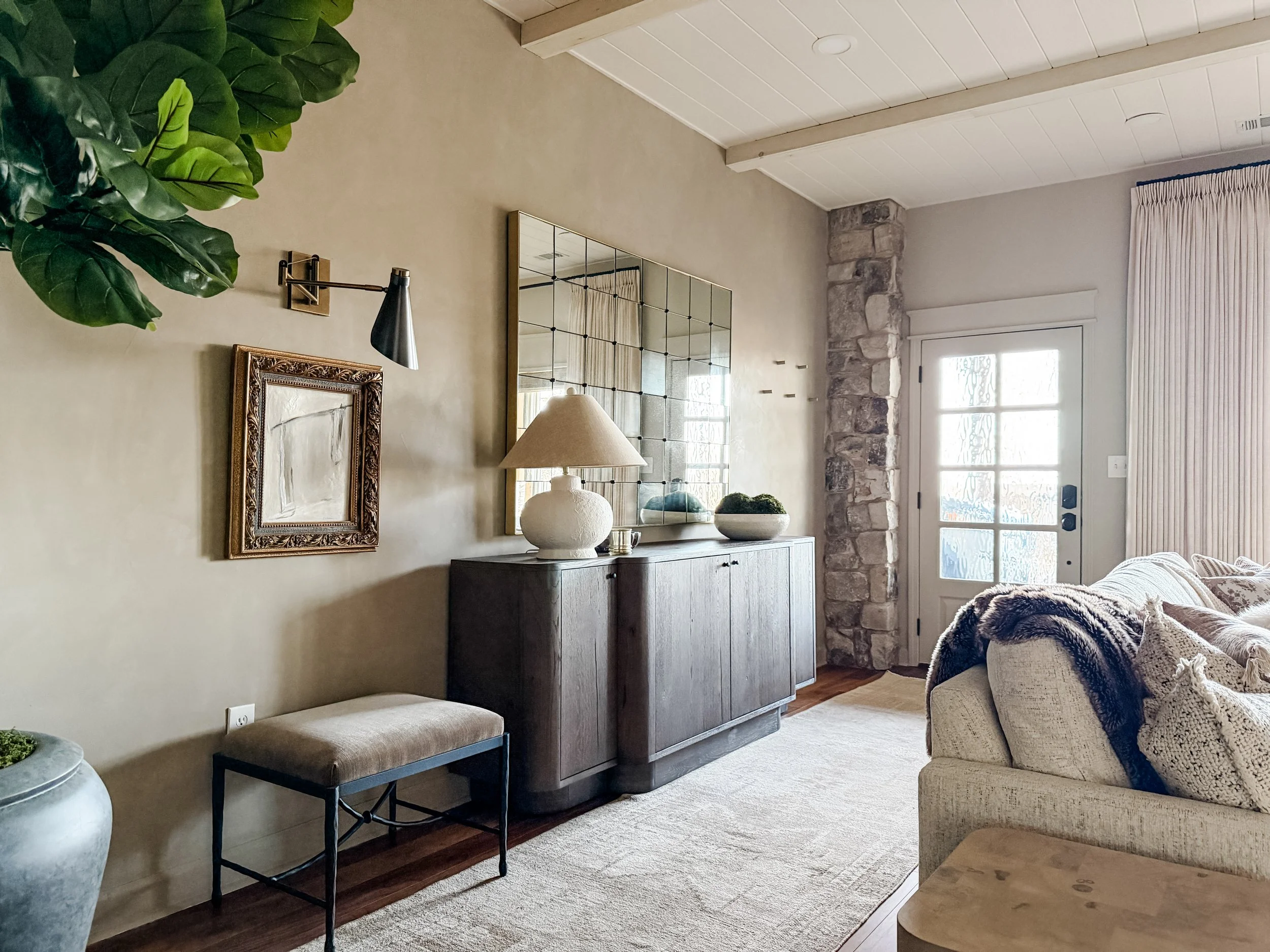 Warm living room with layered textures, wood beams, and natural stone elements designed by Studio Meadow