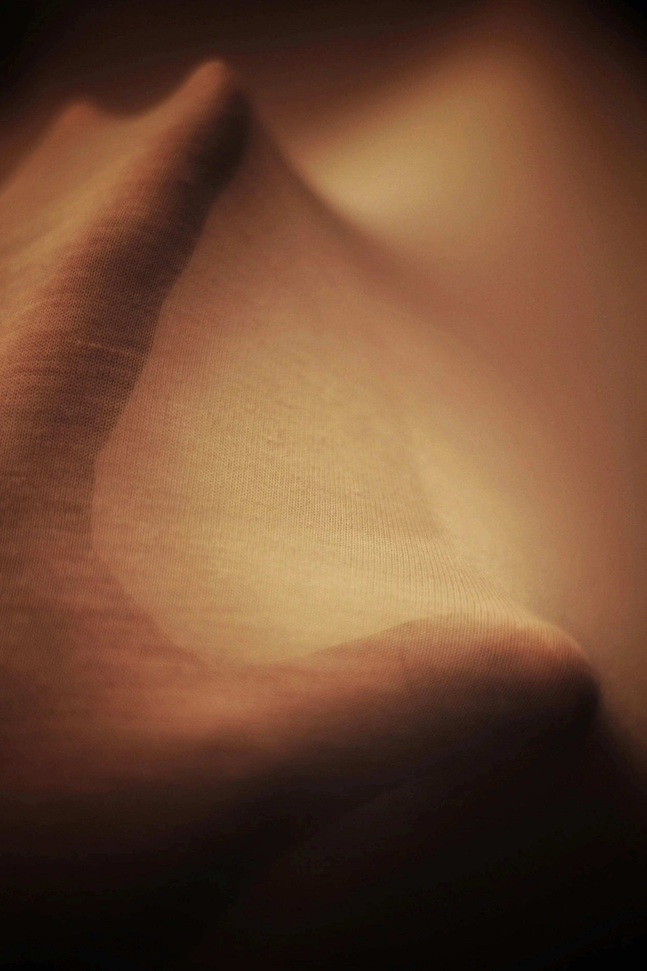 Close-up of a person holding a fabric, possibly a piece of clothing or towel, with soft lighting and a focus on the texture.