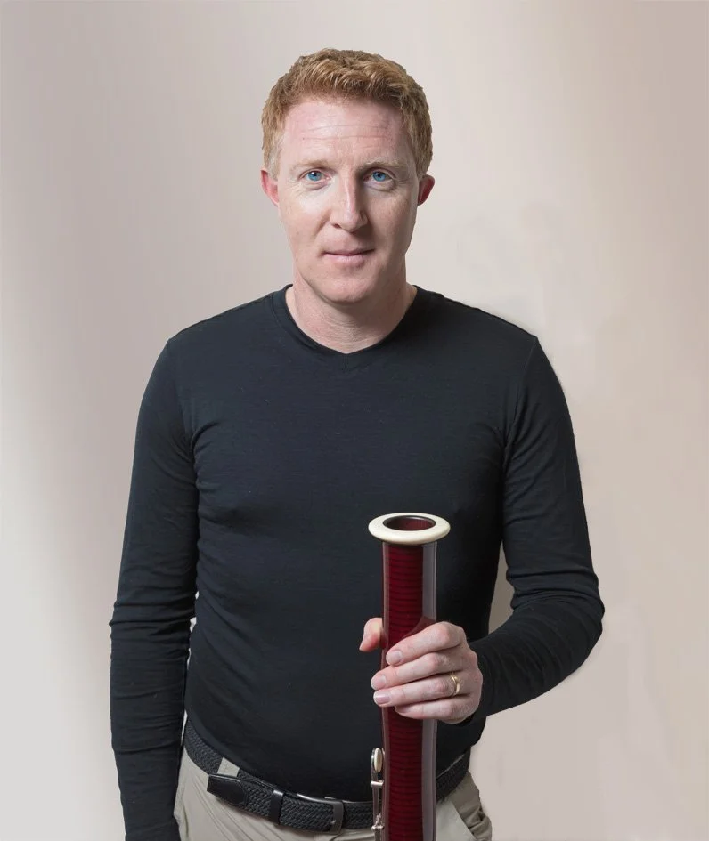 matthew Angus professional musician static pose face-on to camera with bassoon bell in hand