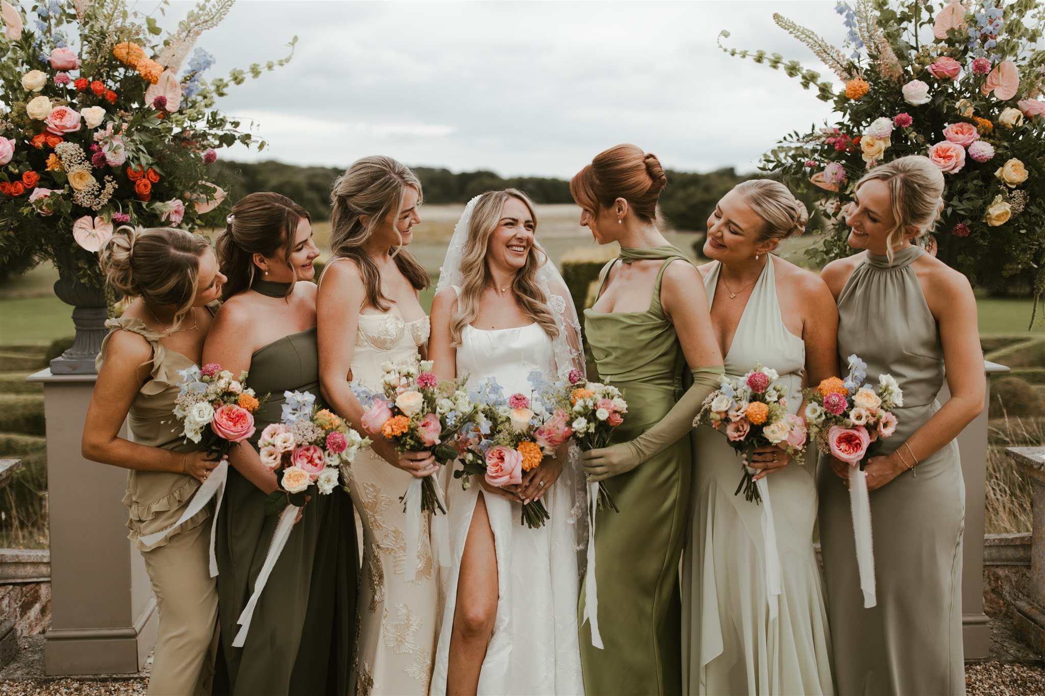 Bridal party wearing green standing together outside holding wedding bouquets