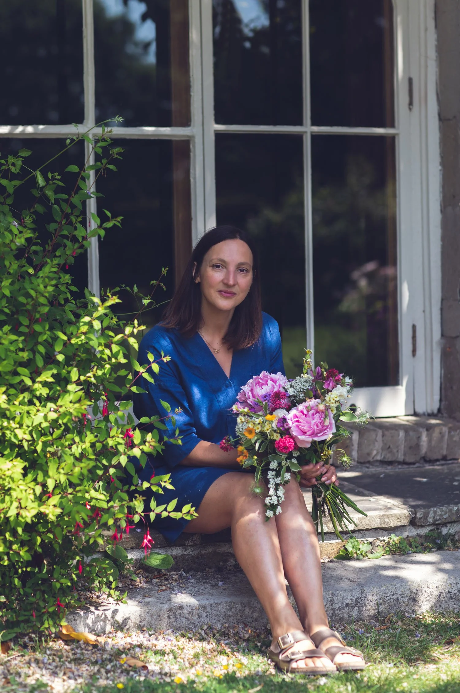 Kent and London based wedding florist sat on step holding seasonal bouquet of flowers