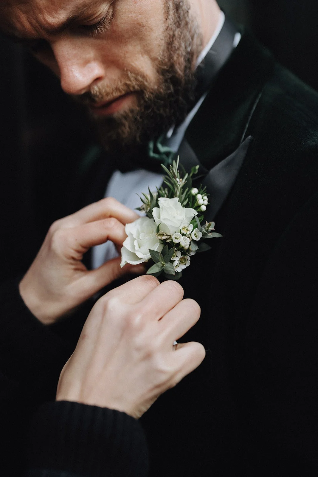 Groomsman adjusting grooms buttonhole flowers