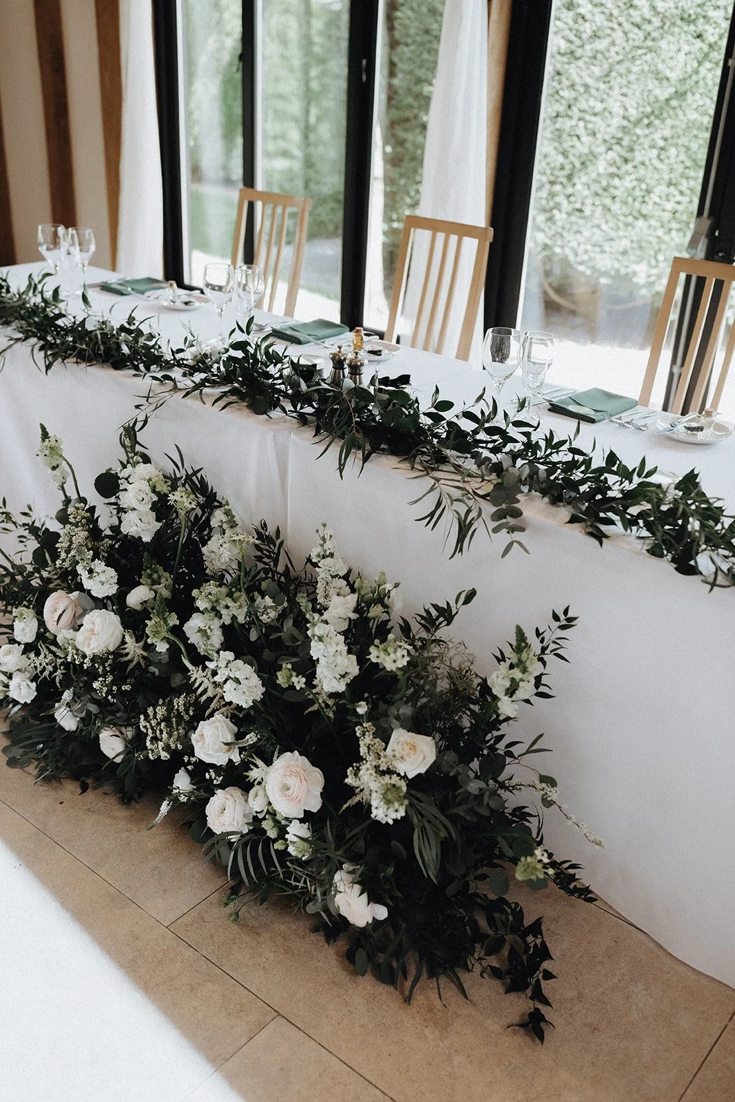 moody-blooms-wedding-flower-packages-top-table-white-greenery-garland.jpg