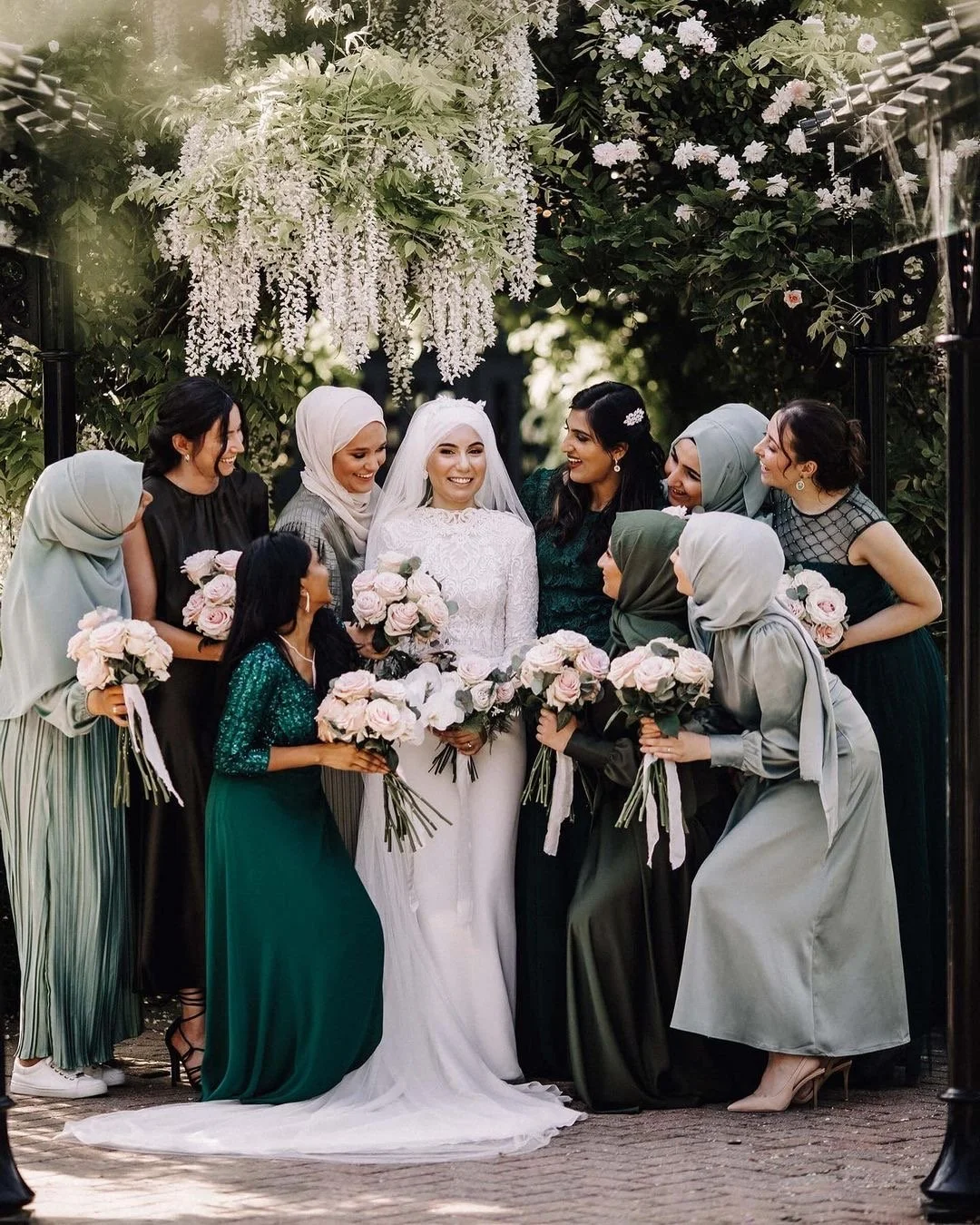 Bridal party wearing green smiling at bride holding wedding bouquets