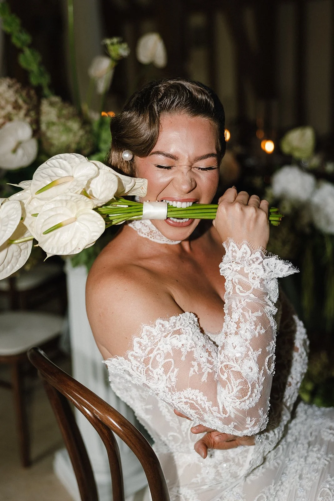 Bride on wedding day biting stems of white anthurium bouquet