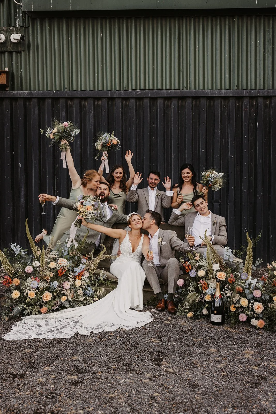 Wedding party with bride and groom smiling laughing with luxury flower arrangements and bouquets