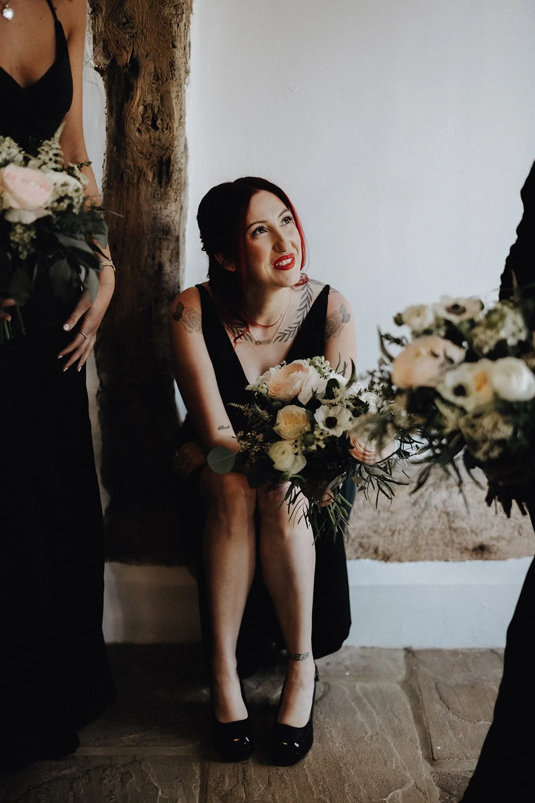 Bridesmaid wearing black sat on step holding luxury wedding bouquet