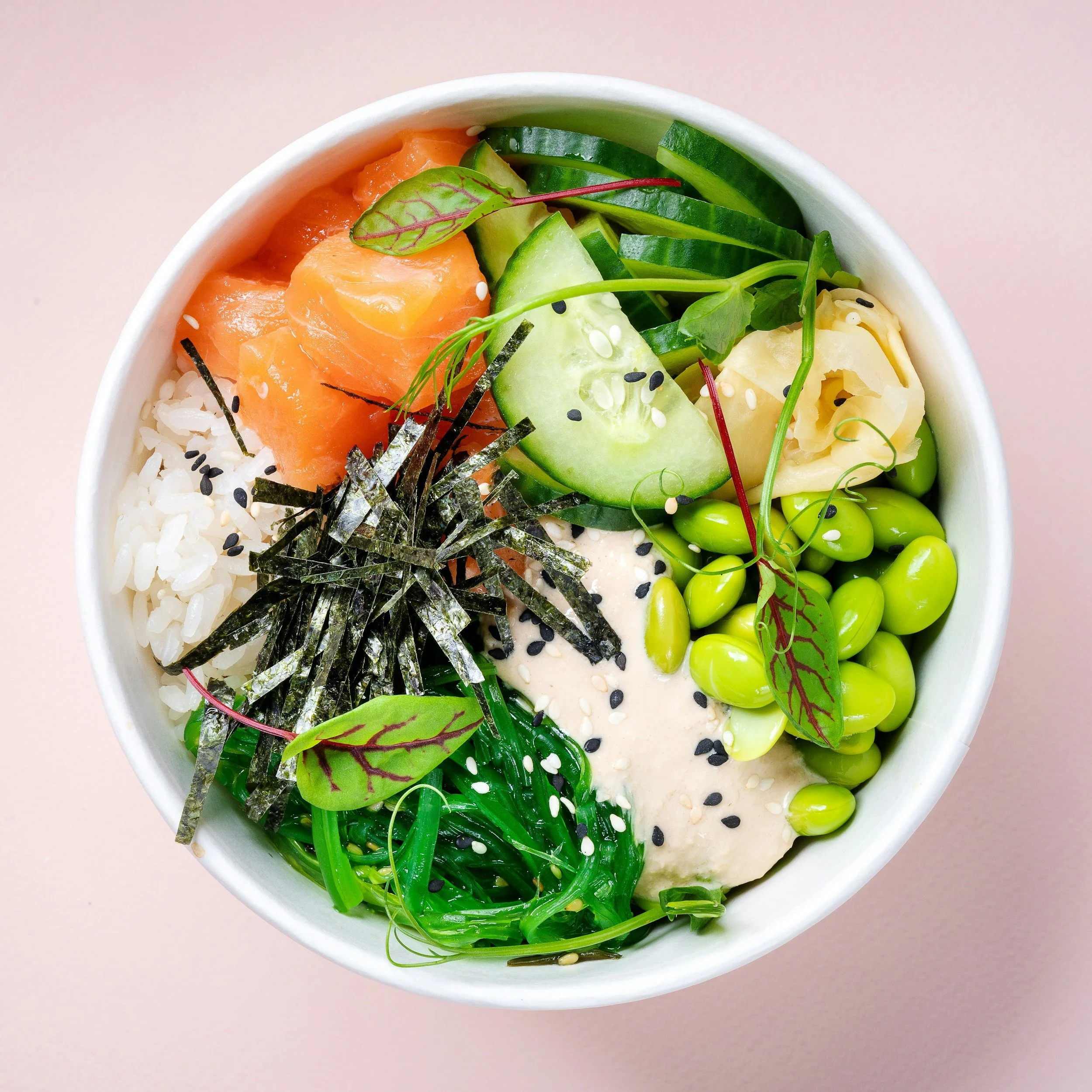 Close-up of a bowl of sushi with various fresh vegetables, seaweed, and sesame seeds from soul bowl