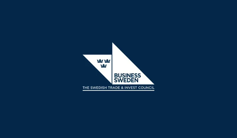 Logo of Business Sweden with a navy blue background and a geometric design featuring a white triangle with a crown symbol, and text that reads 'BUSINESS SWEDEN' and 'THE SWEDISH TRADE & INVEST COUNCIL'.