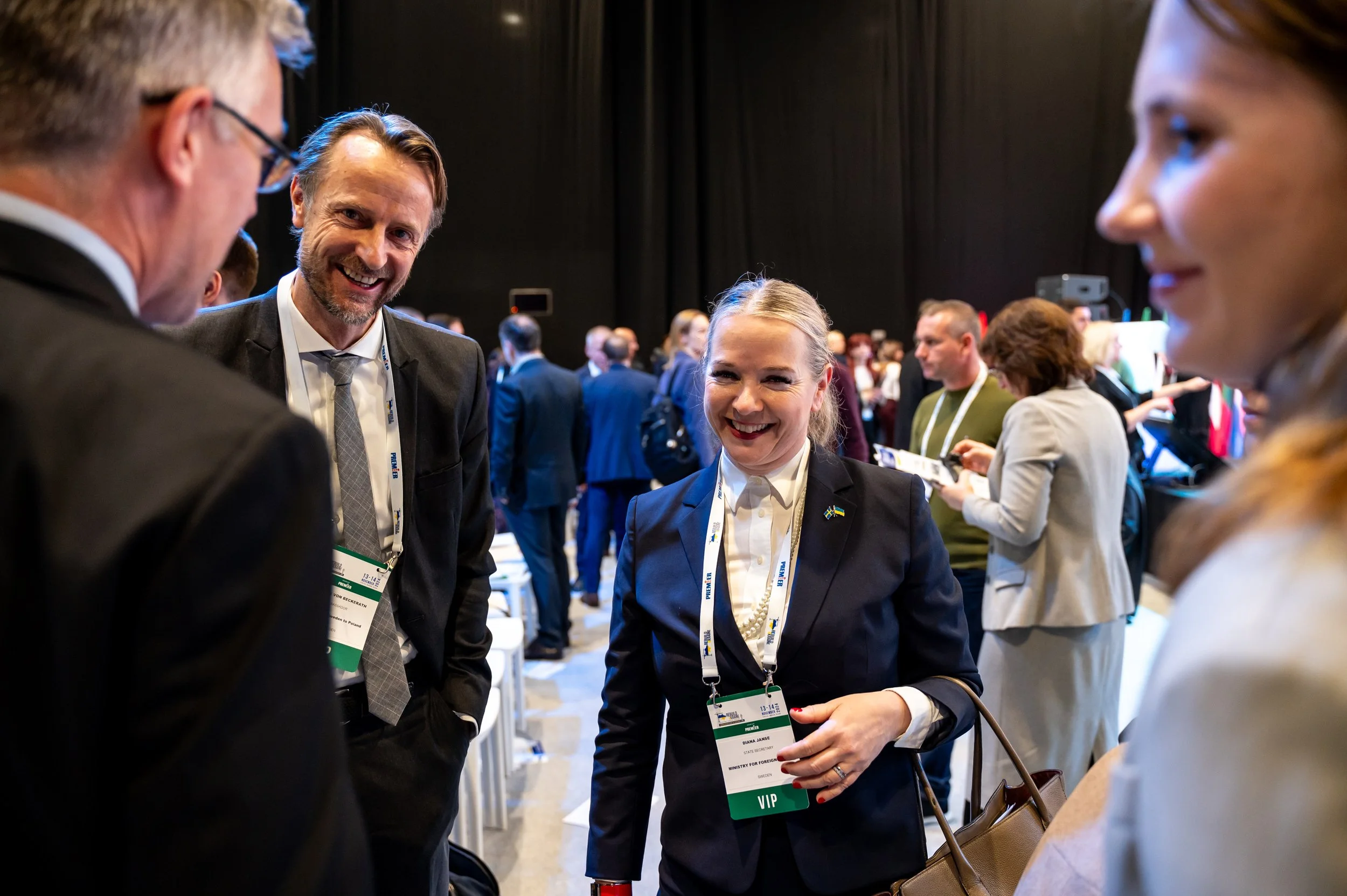 Group of professionals at a conference, engaging in conversation in a busy event space.