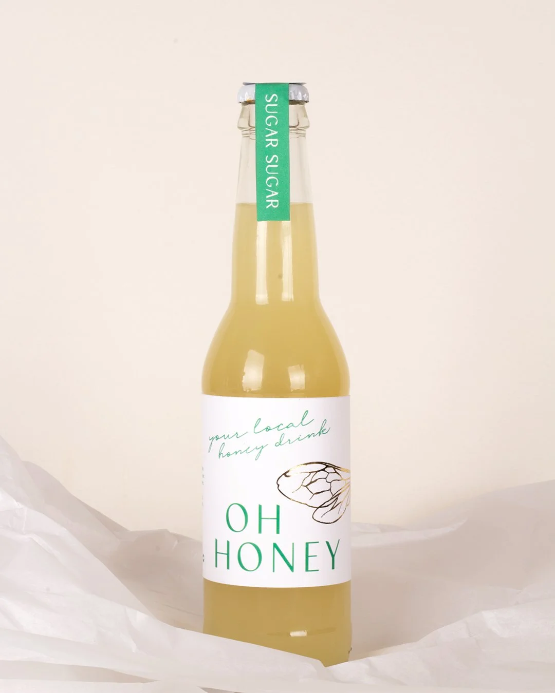 lemonade packaging with minimal label design, delicate line illustrations and subtle gold foil bee wing details, styled with soft, natural photography
