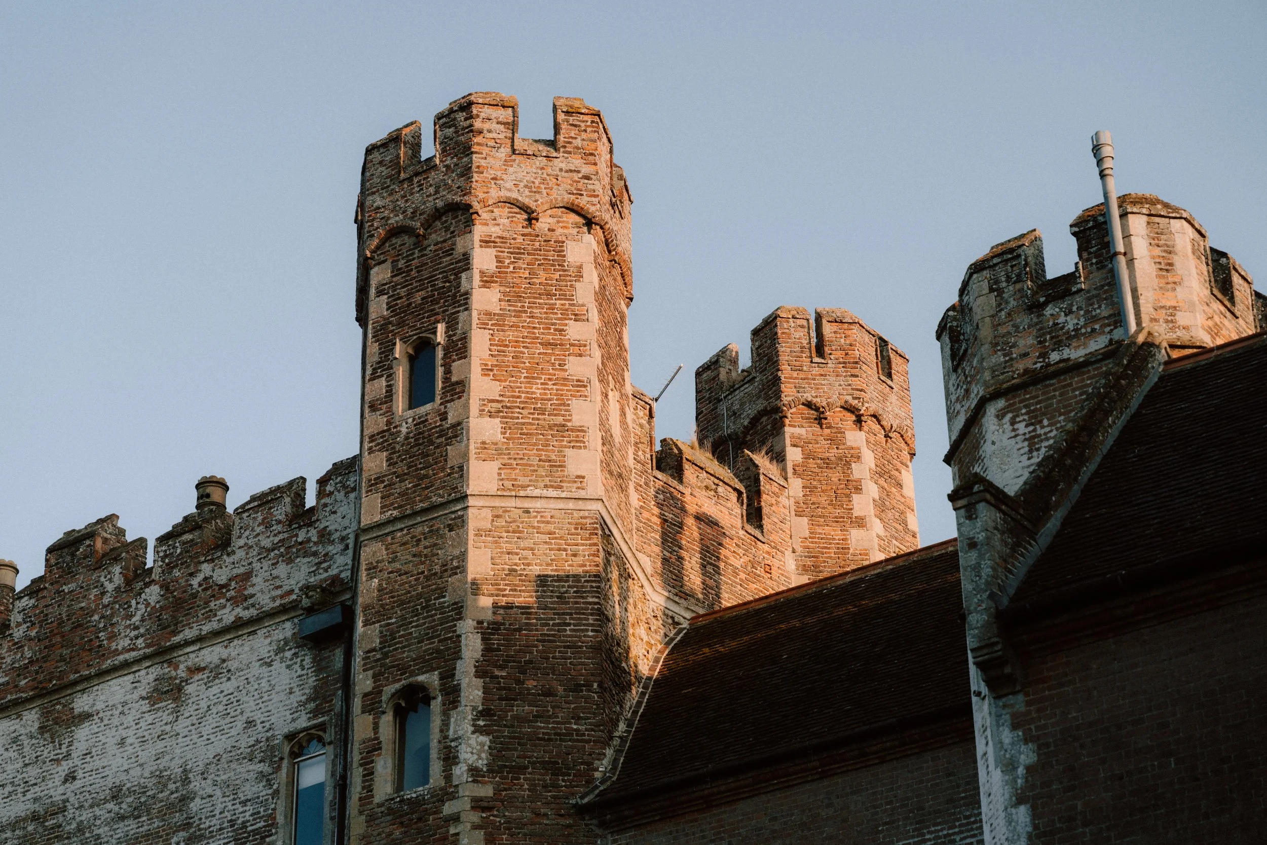 A historic brick castle with towers and battlements under a clear sky.