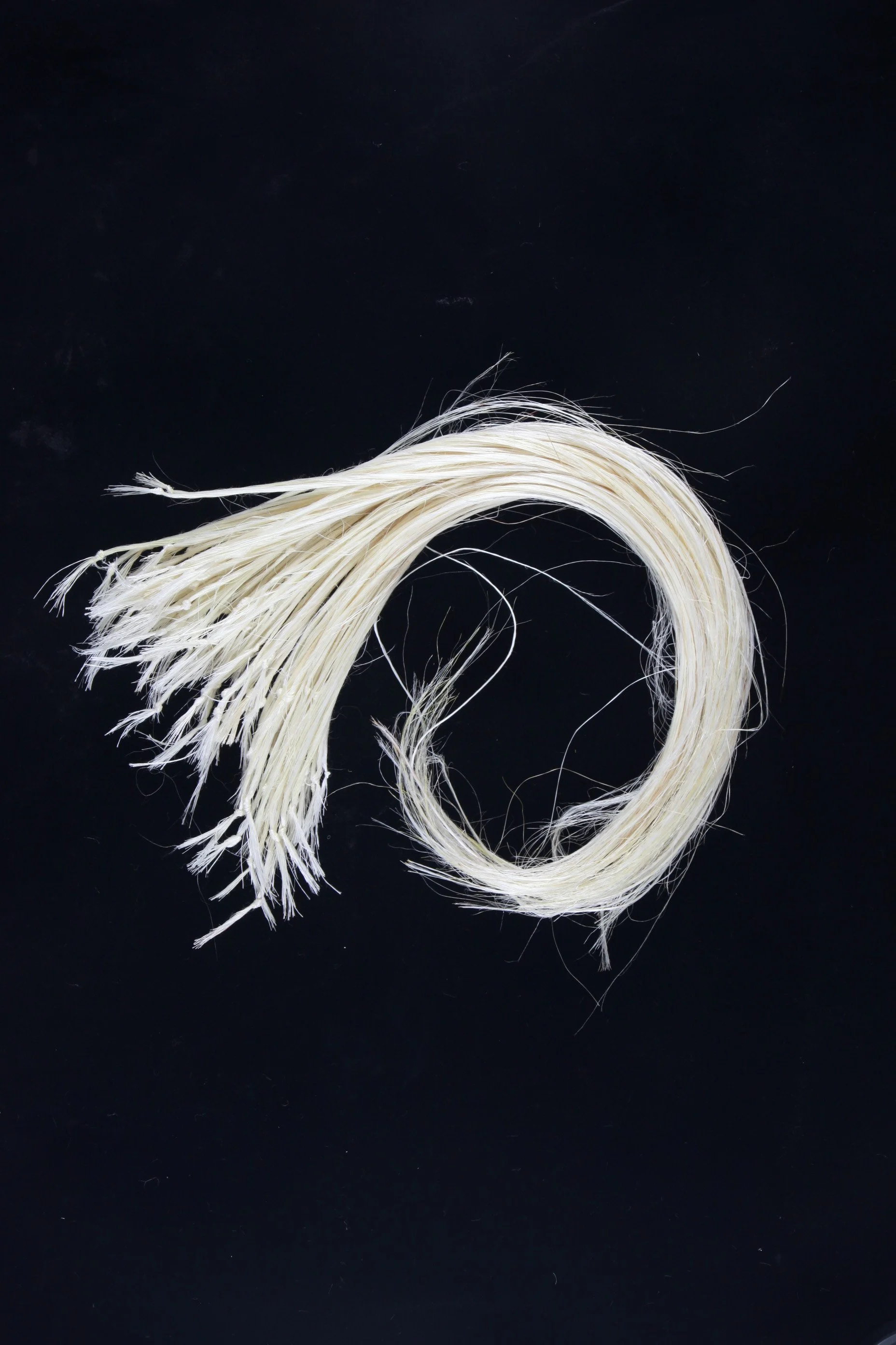 Raw muka fibres arranged in a wave shape, symbolising natural flow and traditional Māori weaving materials.