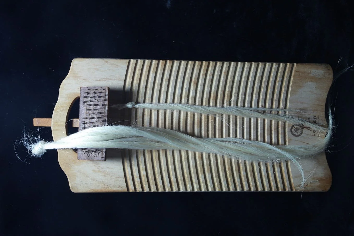 Silk raw muka fibre with hand tool brush on wooden board, featured on thesis cover, symbolising craftsmanship and traditional fibre knowledge.