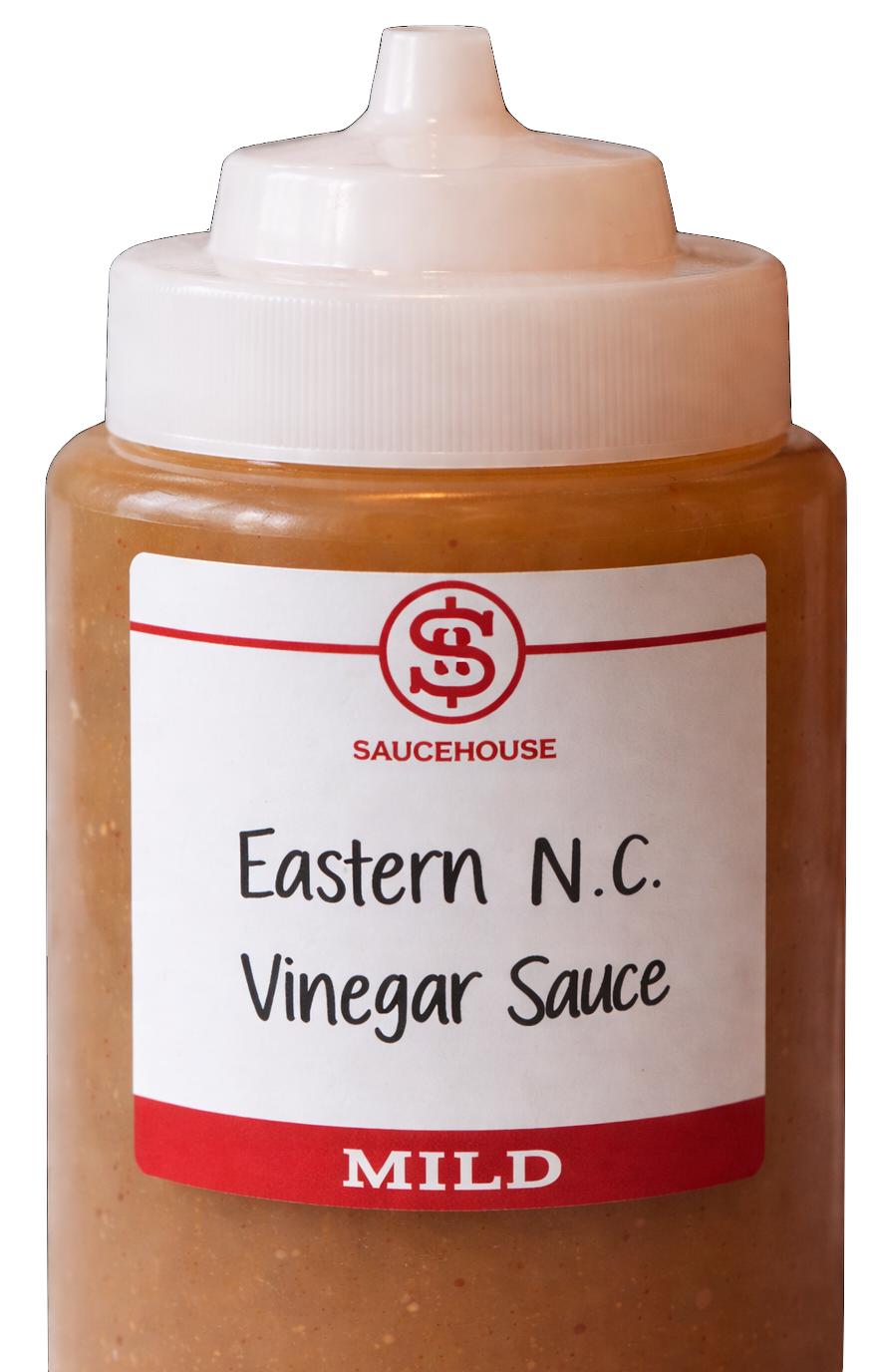 Close-up of a squeeze bottle labeled 'Eastern N.C. Vinegar Sauce' with a red and white label from the brand Saucehouse, indicating a mild flavor.