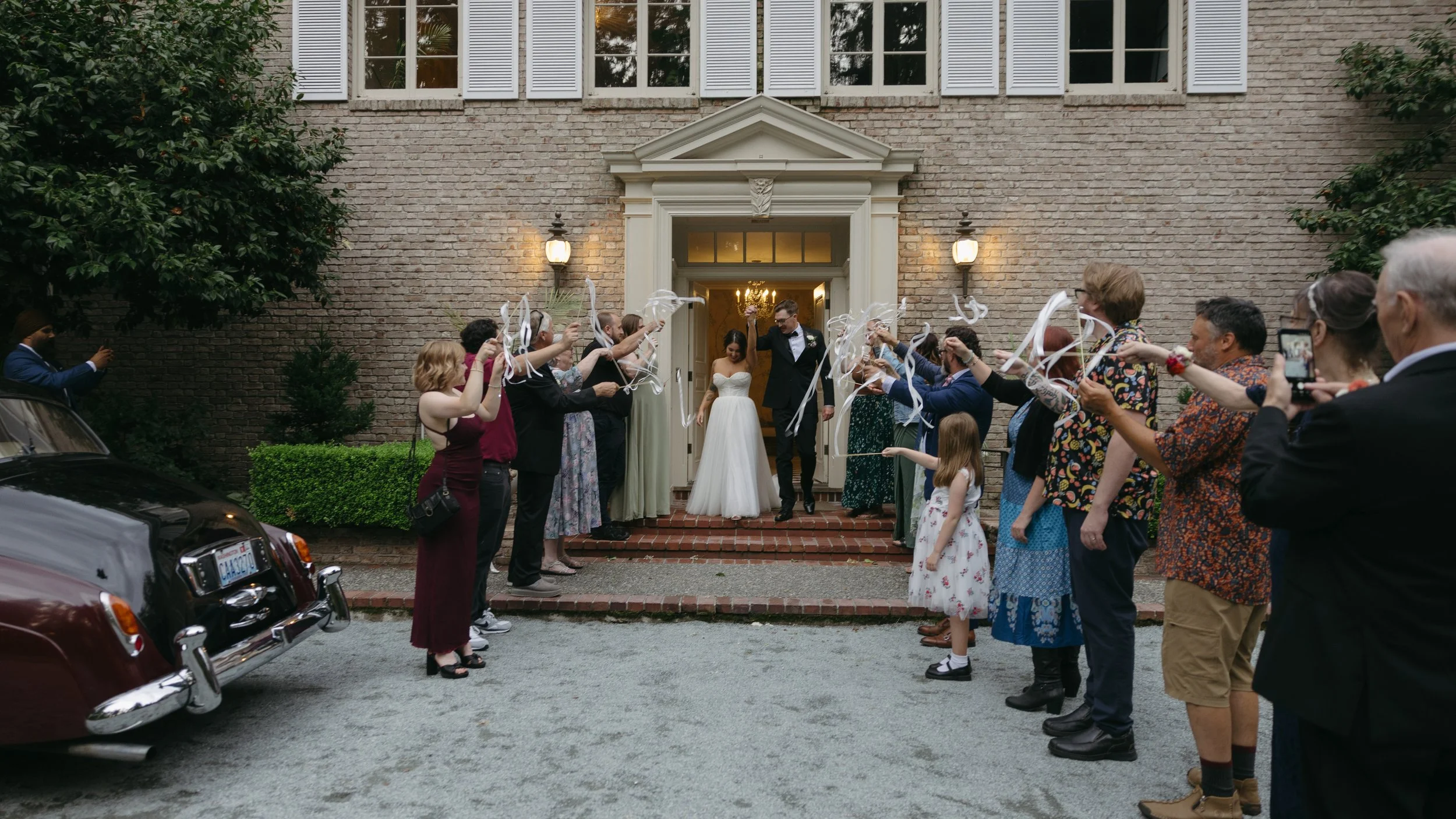 Bride and groom exit during a sendoff as their wedding guests throw ribbons in celebration at a European inspired Lakewold Gardens wedding in Seattle