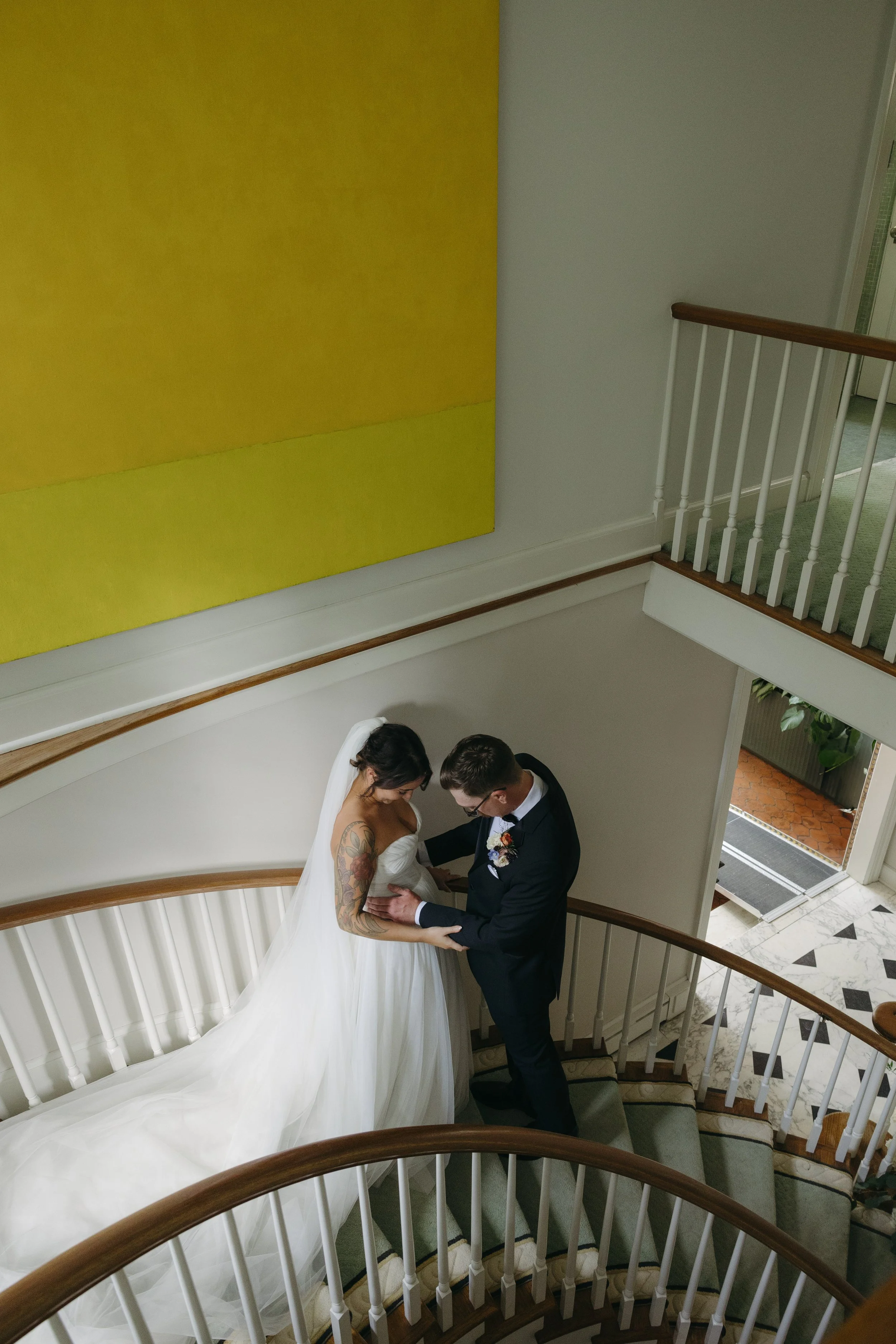 A bride and groom standing on a staircase, holding hands and looking at each other at a European inspired Lakewold Gardens wedding in Seattle