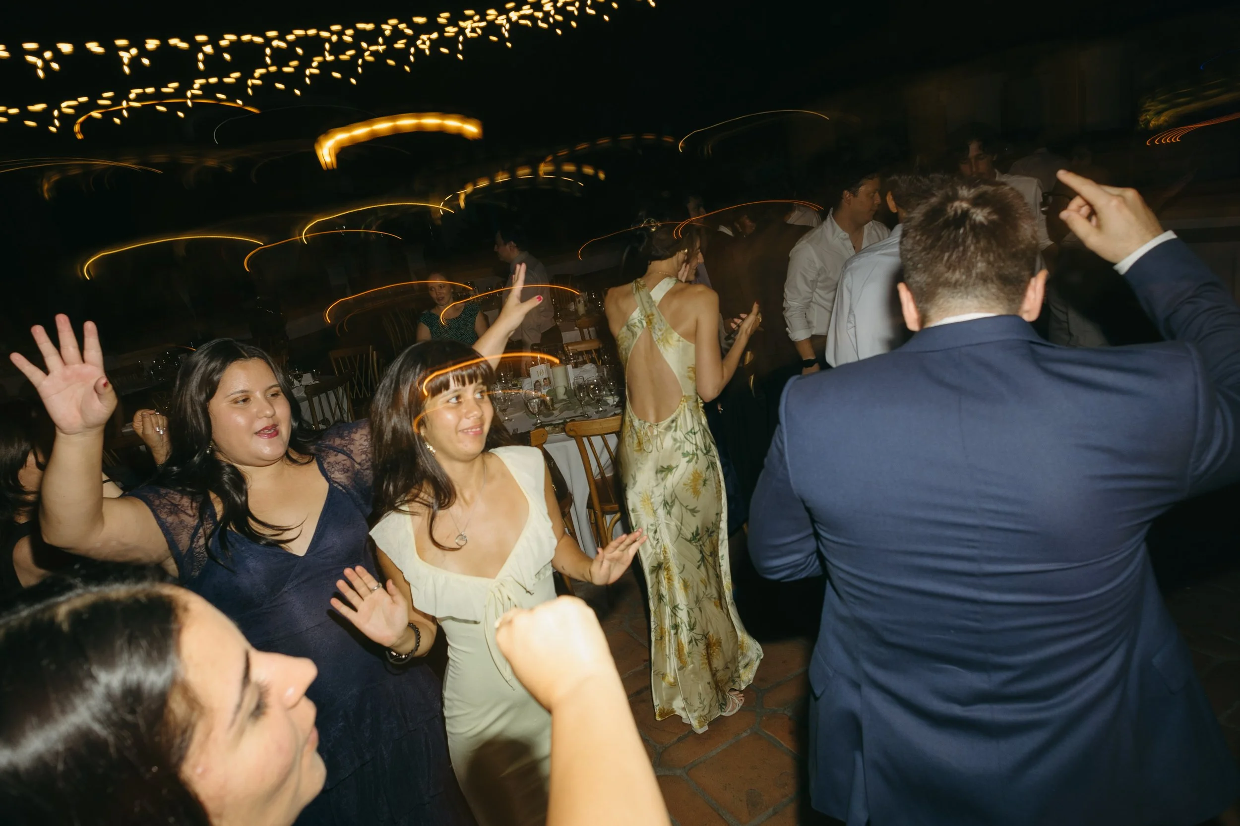 People dancing and enjoying themselves at a party or celebration with blurred motion effects, dim lighting, and festive atmosphere.