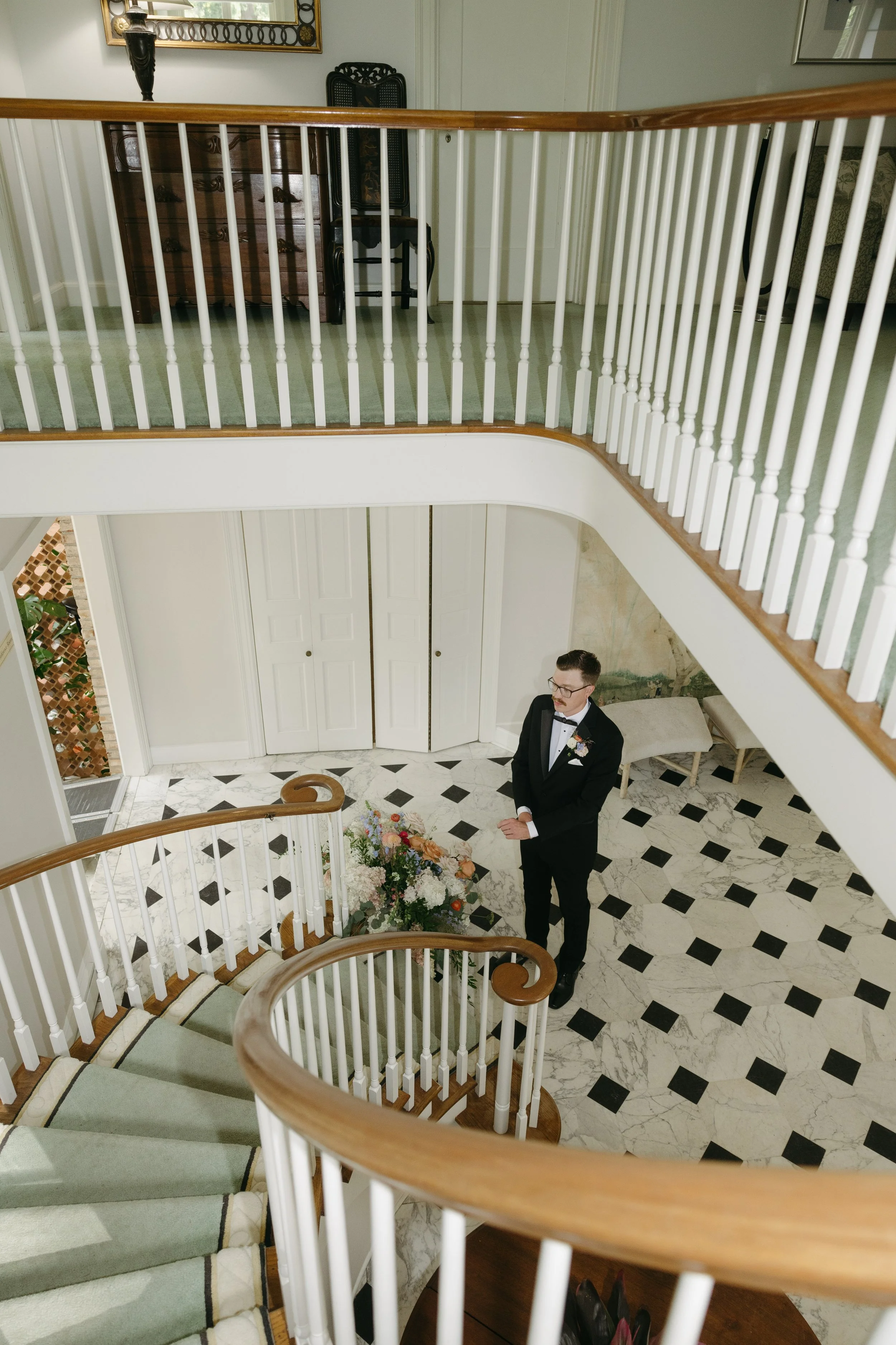 A groom waiting at the bottom of a staircase for his bride at a European inspired Lakewold Gardens wedding in Seattle