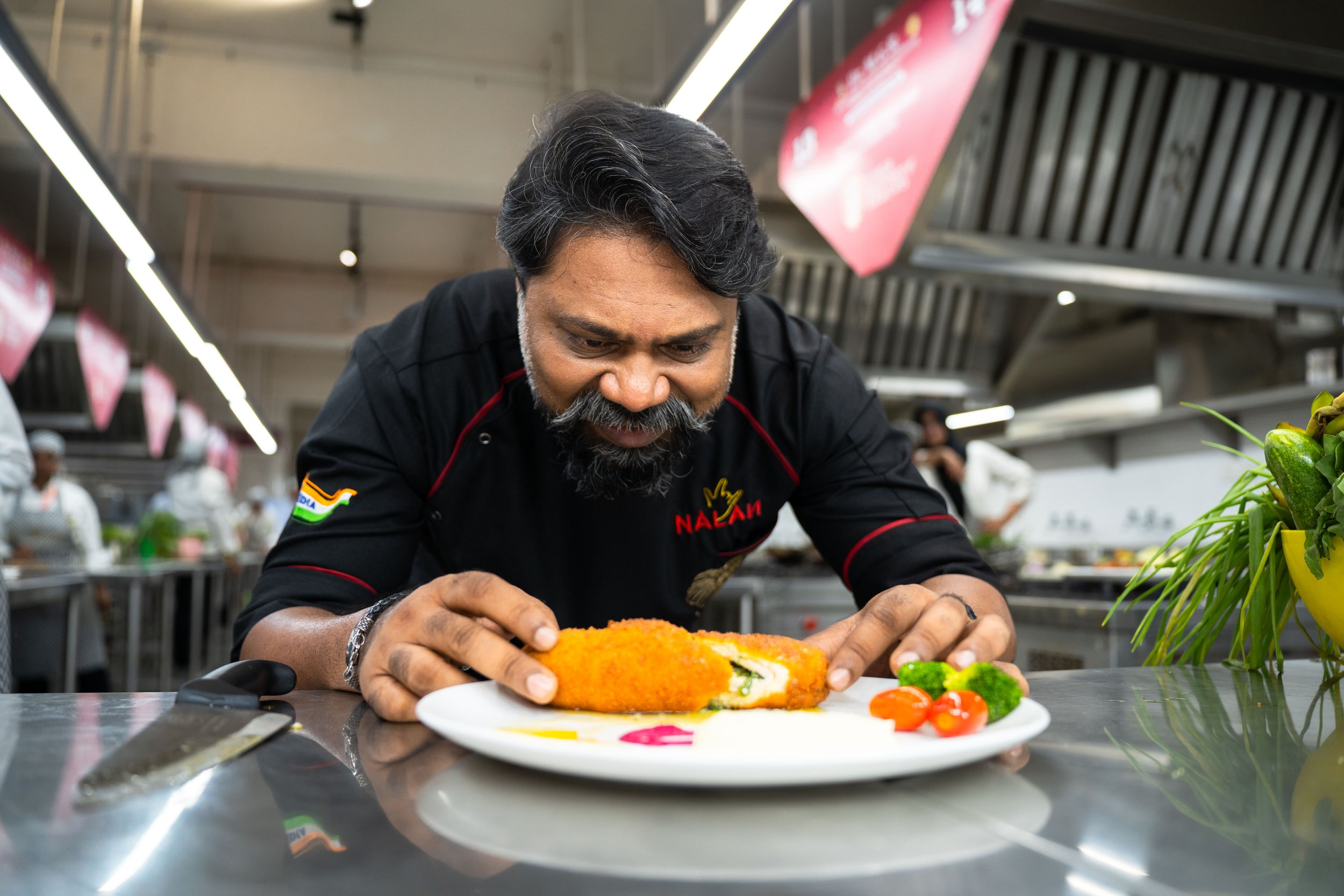 A chef cooking at a kitchen stove surrounded by fresh vegetables and cooking ingredients, with a festive sparkle overlay.