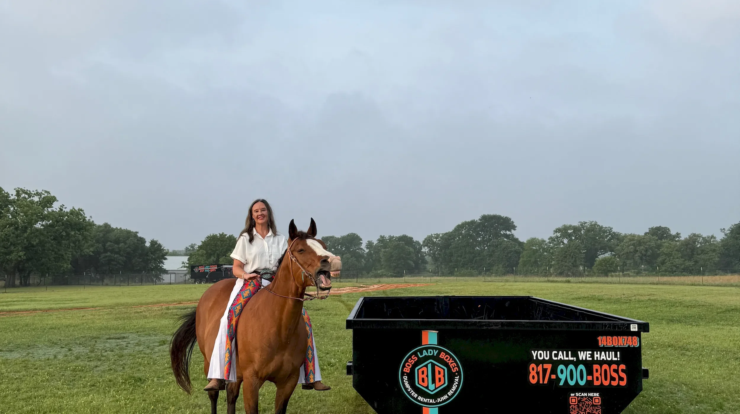 Boss Lady Boxes owner Michelle Lozier with Oakley the horse smiling beside a 14-yard dumpster for dumpster rental and junk removal in Glen Rose, Texas.
