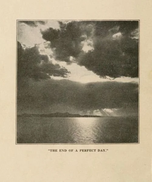 Black and white photograph of a sunset over a body of water with dark clouds in the sky, captioned 'The End of a Perfect Day.'