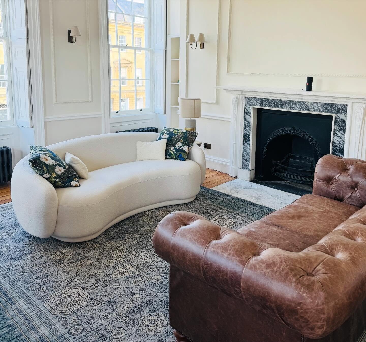 Georgian interiors were about symmetry and proportion, not matching furniture sets. 

I wanted the Chesterfield to anchor this room in history and I think the curved contemporary boucle sofa does a fine job of balancing that with modern living. The P