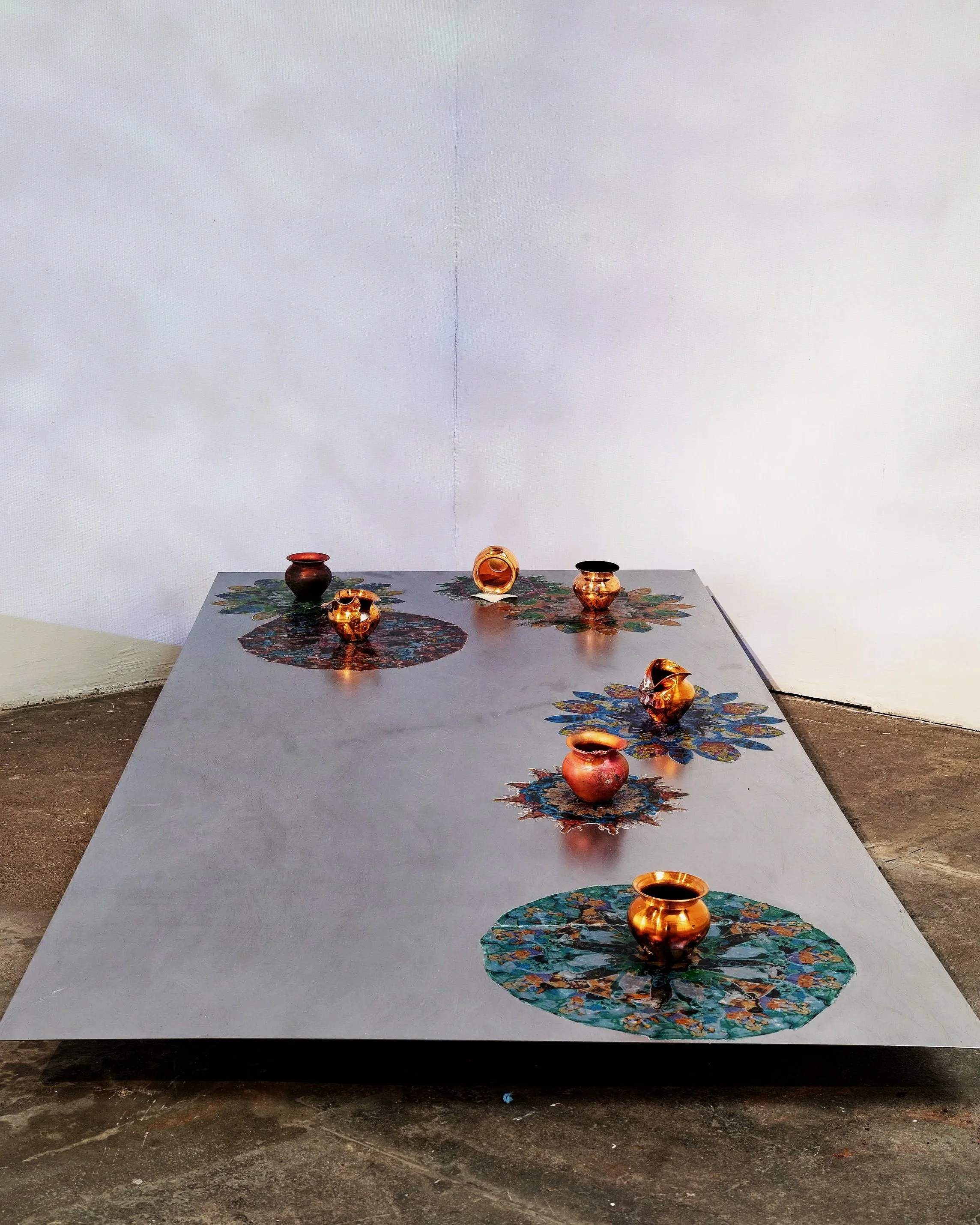 R Godbole 2024 Ganga: Instalation VIew - lota pots, photo transfer mandalas & engraved steel plate at the Copeland Gallery, South London