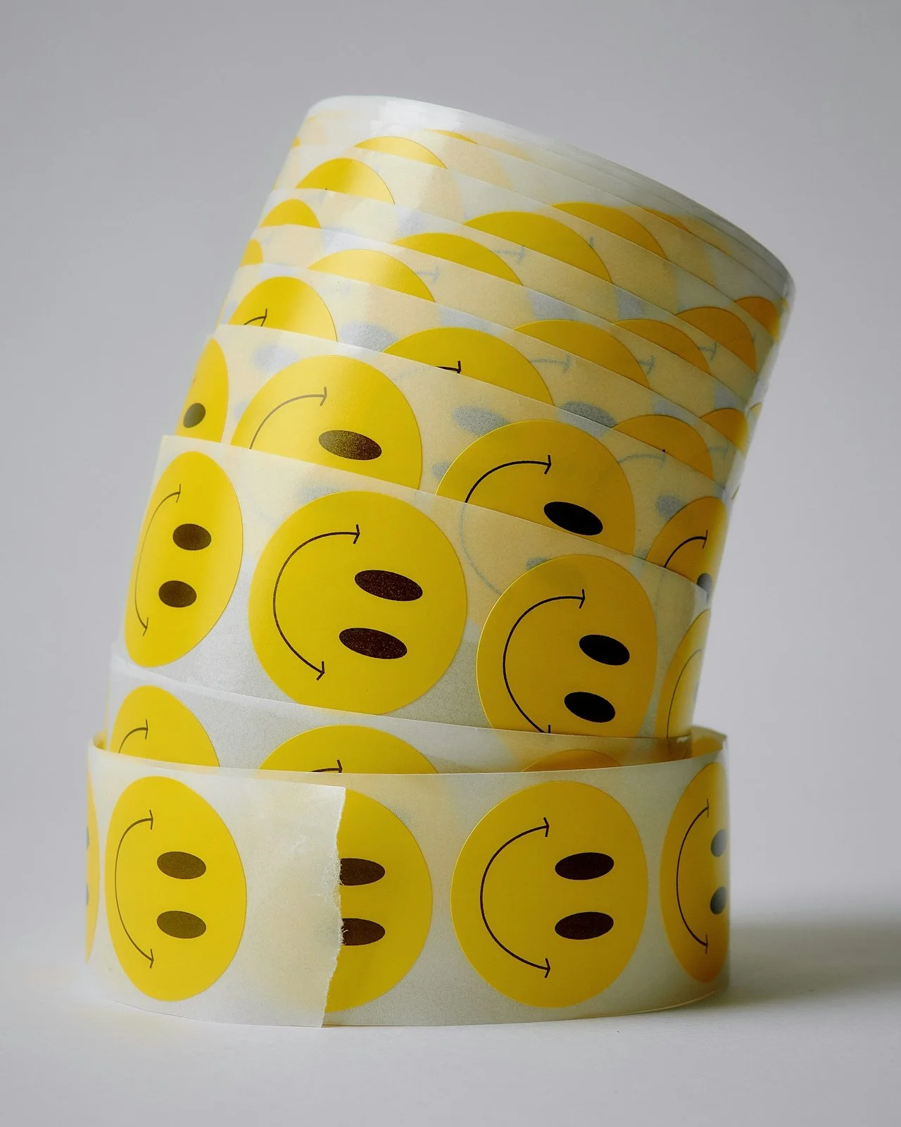 Rolls of yellow smiley face stickers with a happy face and arrow design.