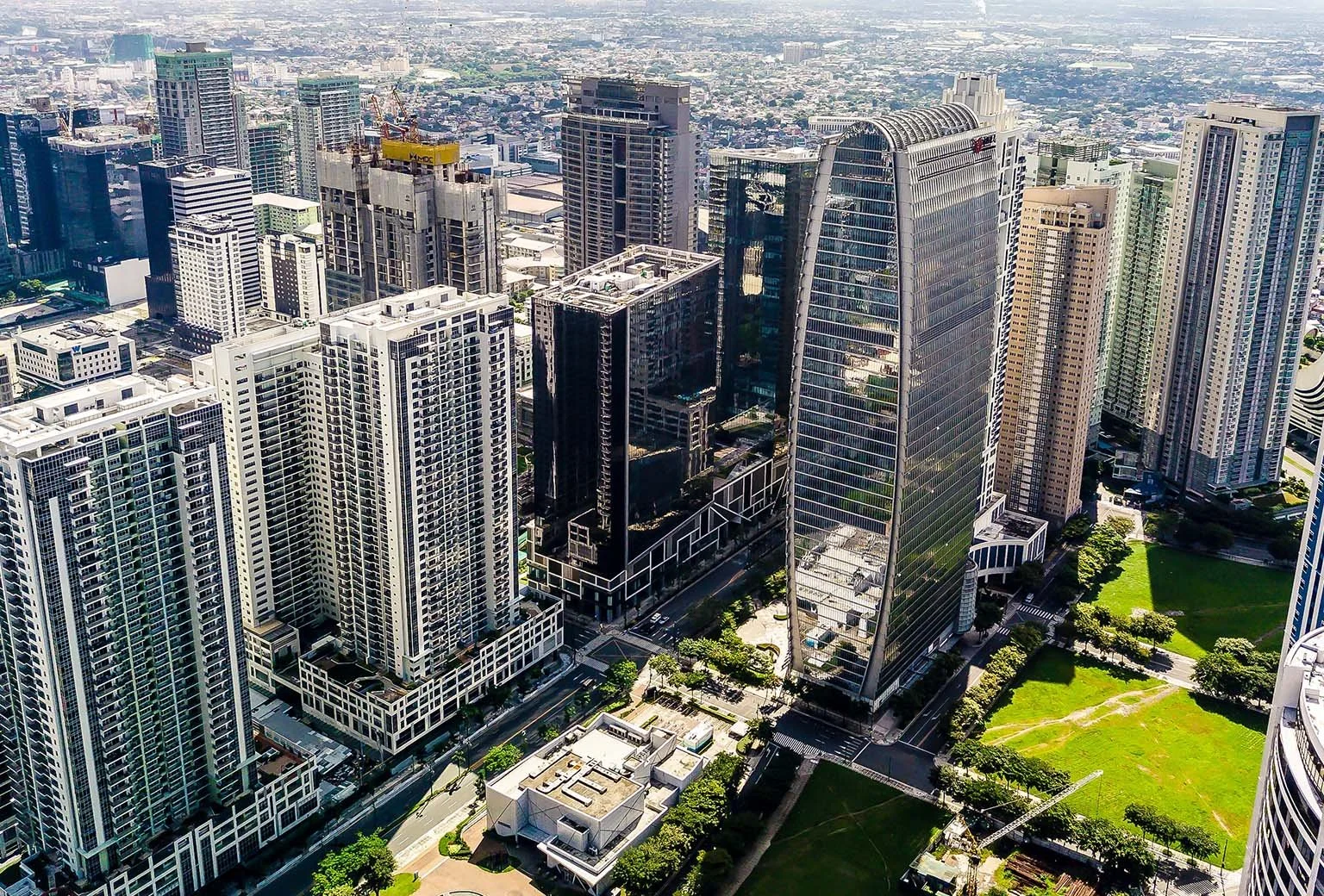 Aerial view of a cityscape with tall skyscrapers, green parks, and streets in a modern downtown area.