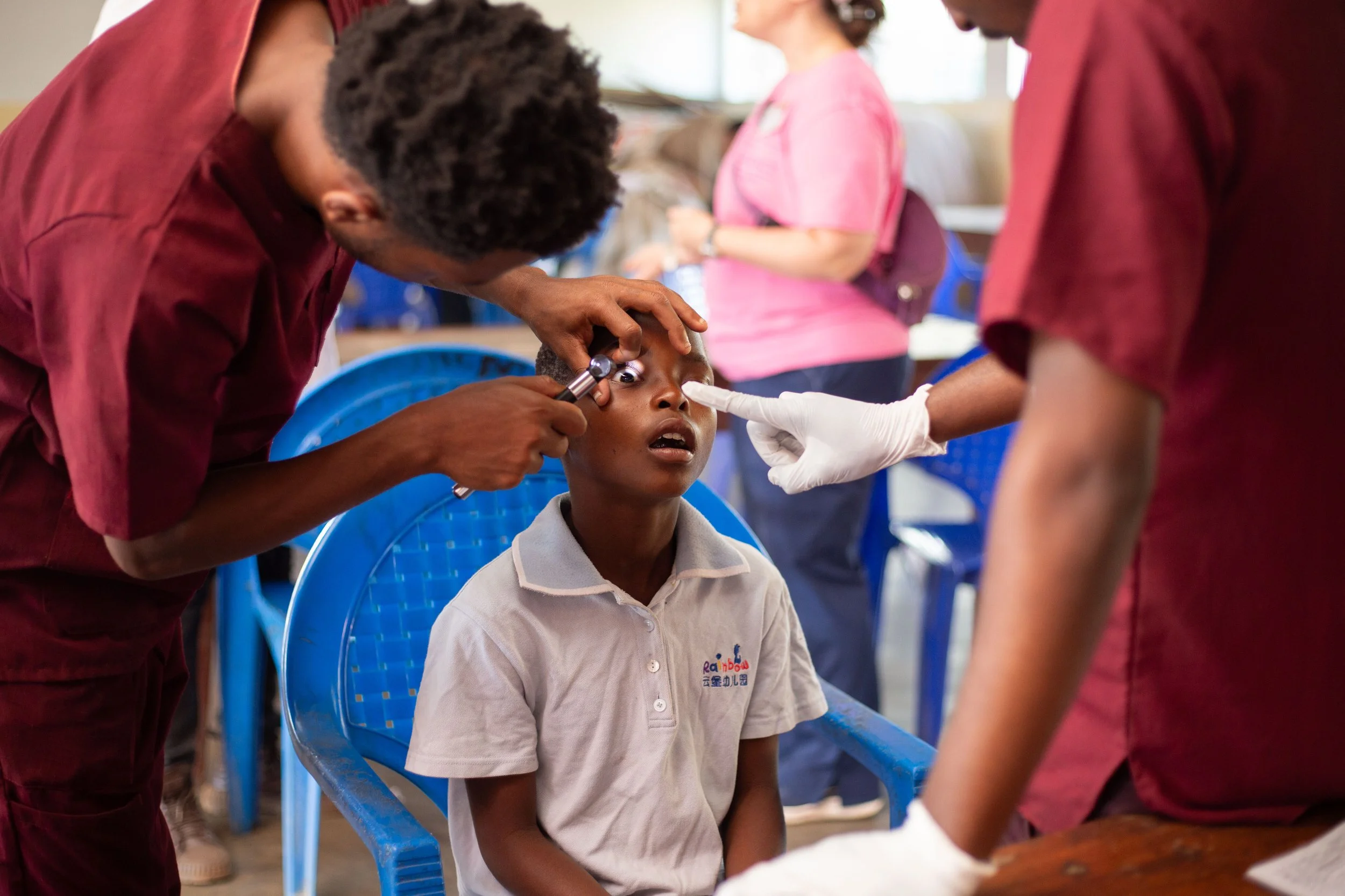 A young boy receiving an eye exam from medical professionals in a healthcare setting.