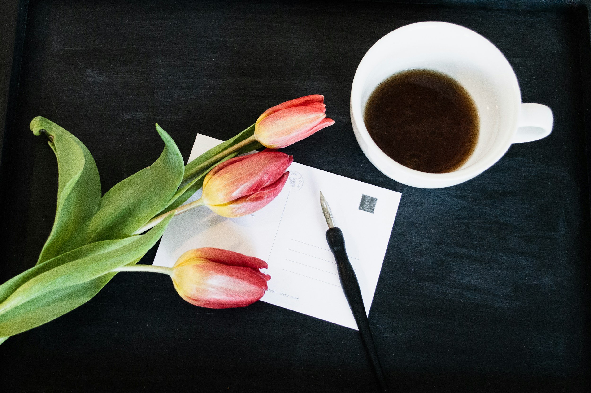 image of postcard with cup of coffee, a pen, and a tulip