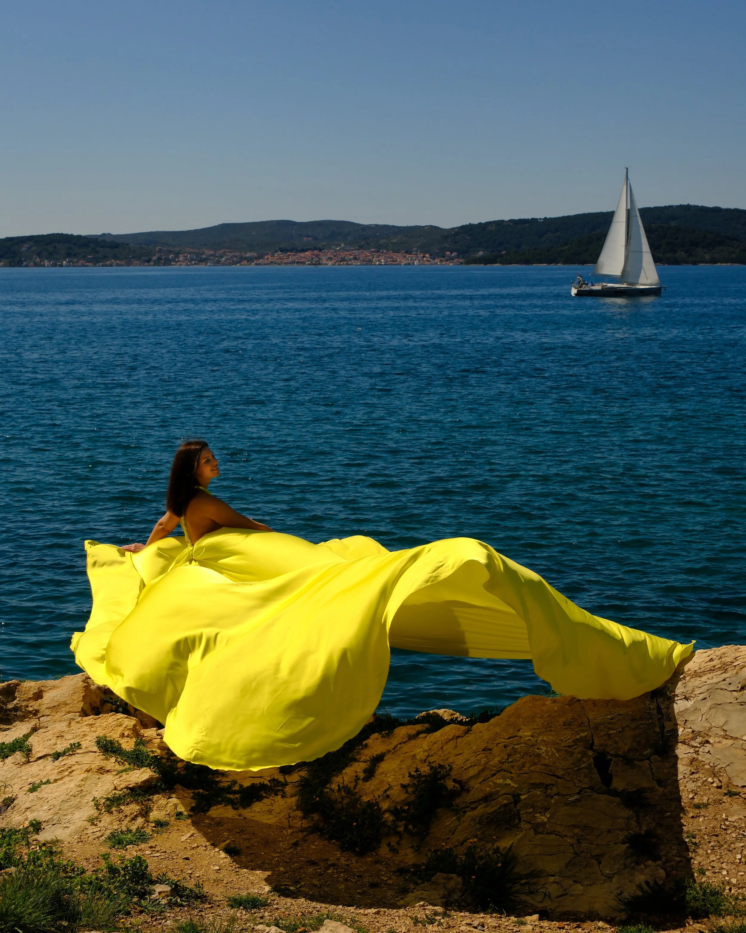 Flying dress photoshoot by the sea in Croatia. Wind, waves and flowing fabric create a natural, elegant and cinematic atmosphere.