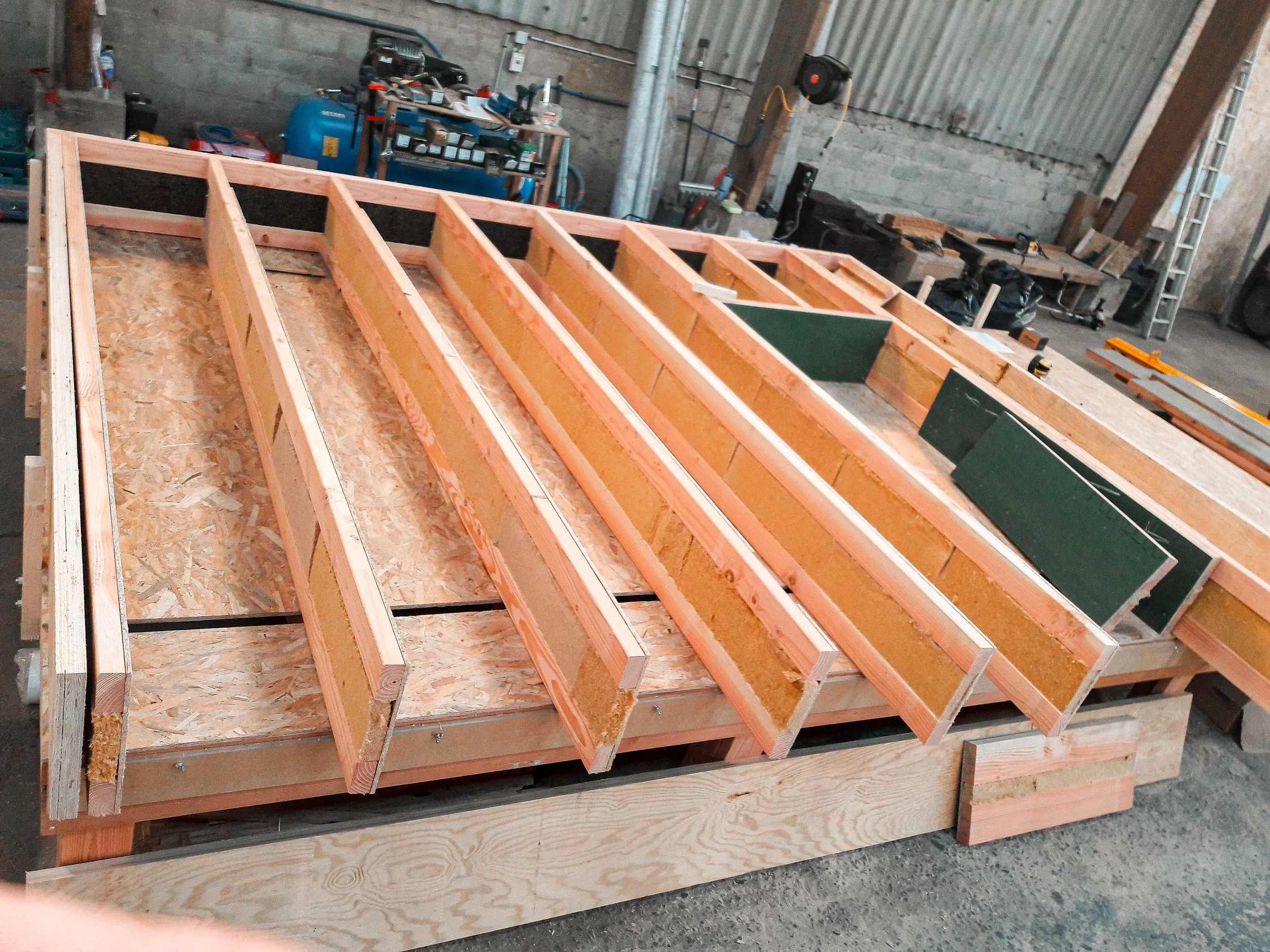 Une structure en bois en cours de construction, probablement pour un meuble ou un cadre, dans un atelier ou un garage.