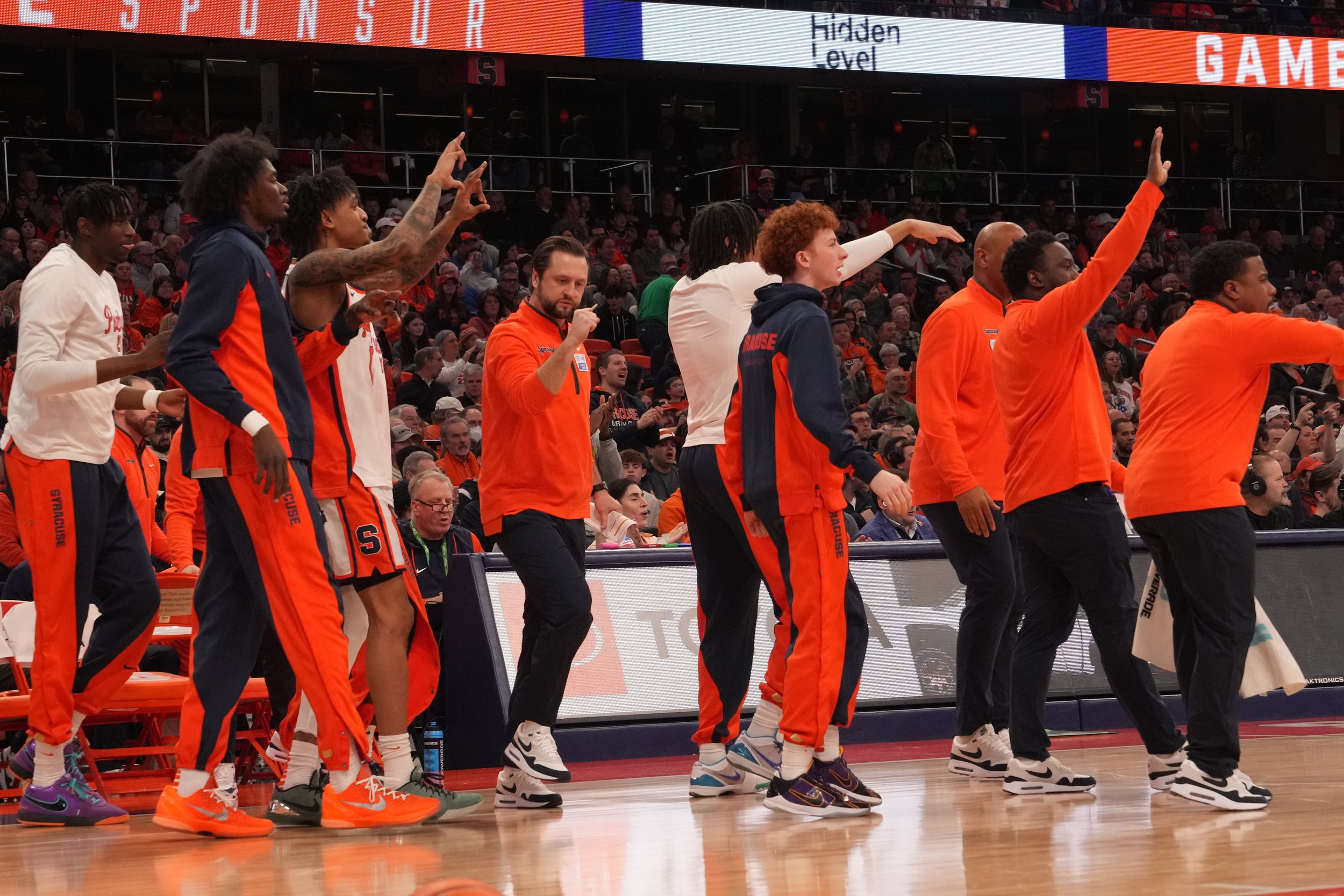 Syracuse basketball players and coaches stretching and warming up on the sidelines during a game at the Dome in Syracuse, New York.