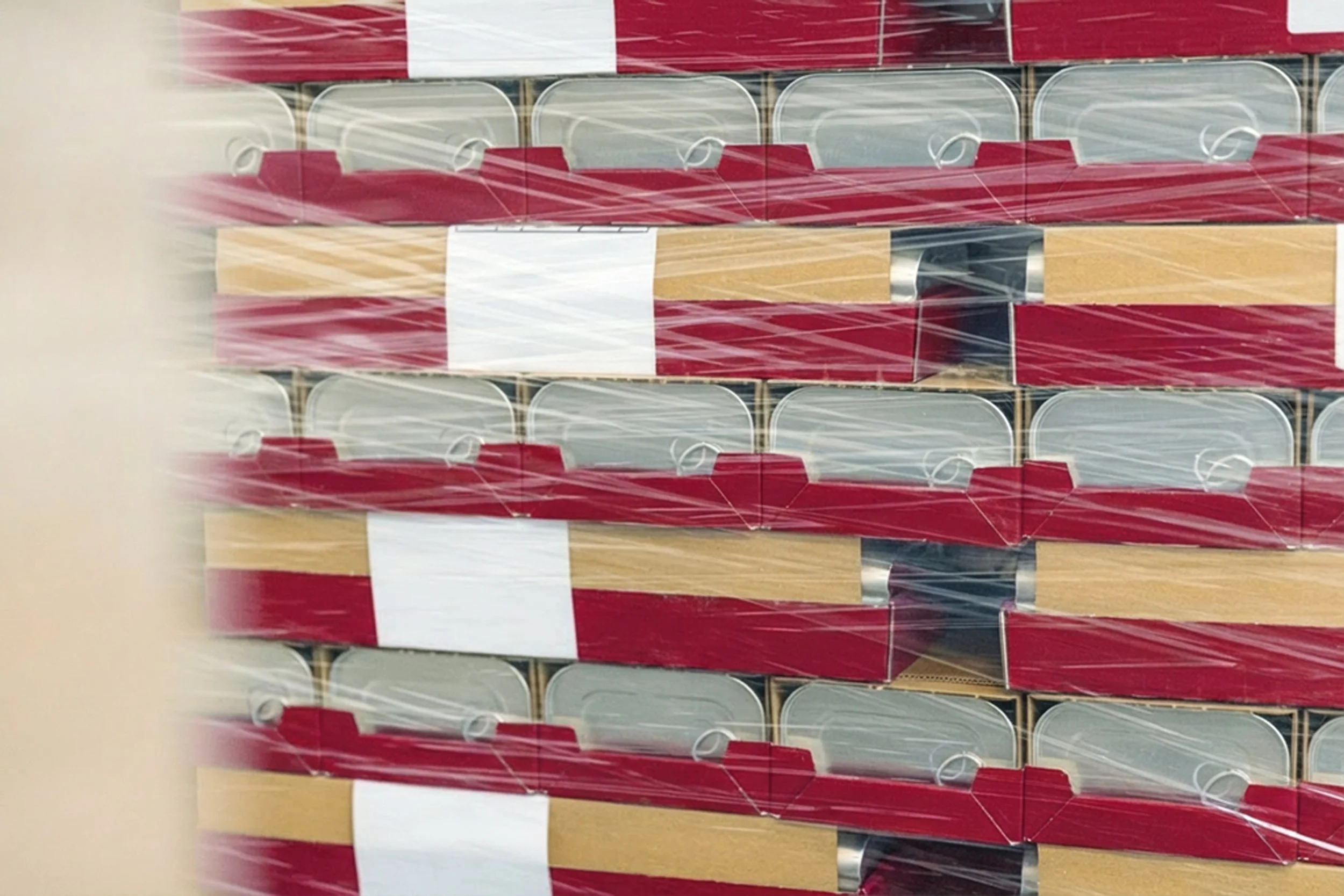 Stacked boxes wrapped in clear plastic with red, white, and black packaging design.