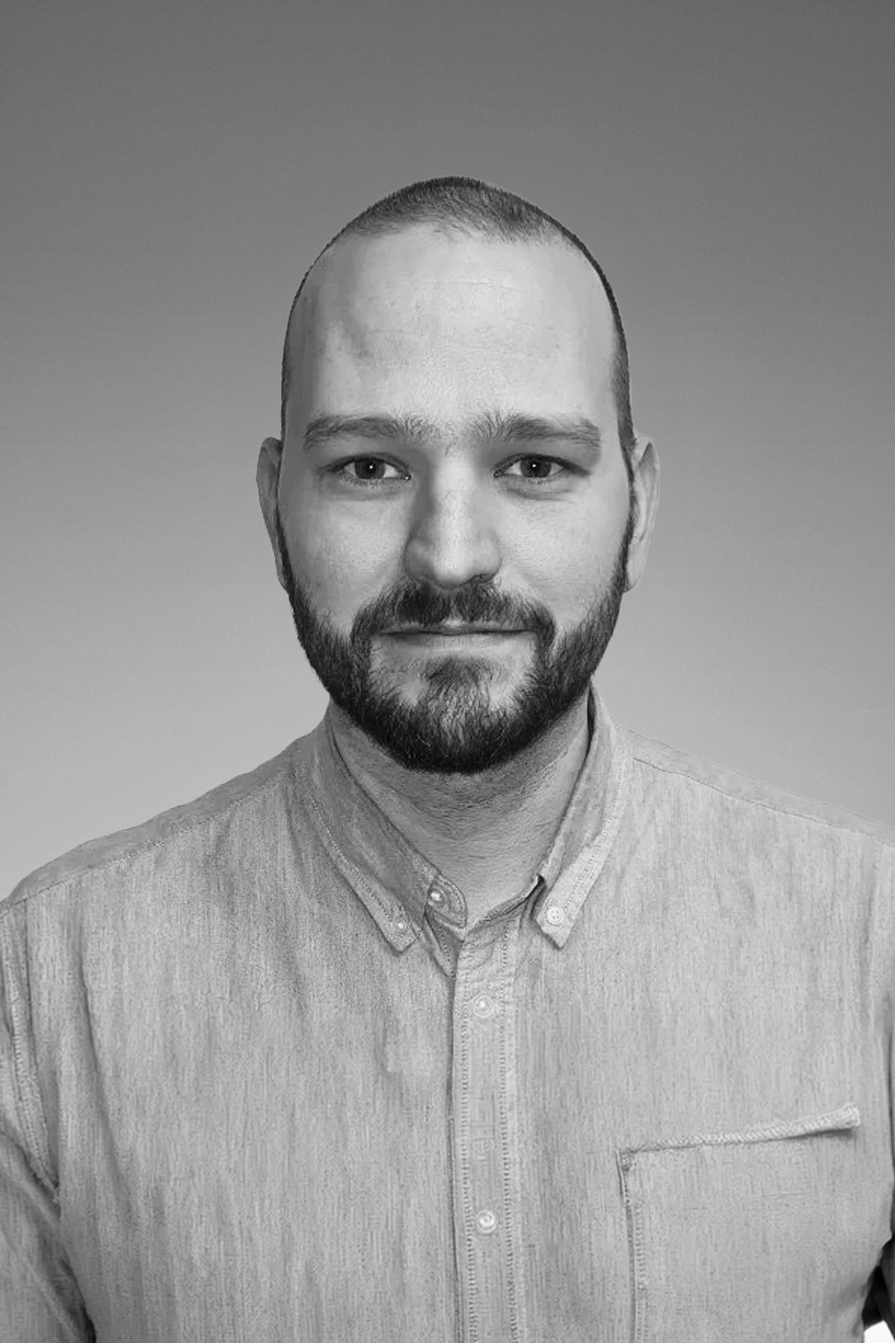 Black and white portrait of a man with a beard, short hair, wearing a collared shirt, facing forward against a plain background.